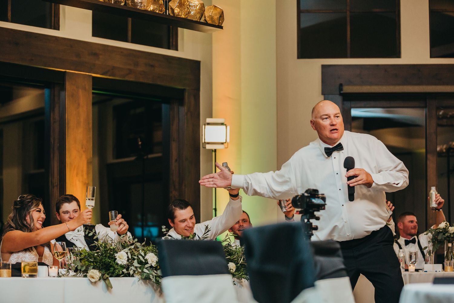 A speaker giving an animated toast during the wedding reception dinner.
