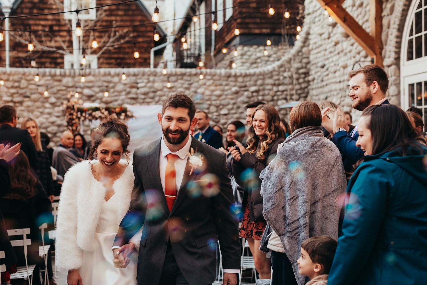 Wedding guests gather in a rustic brick venue during a winter celebration.