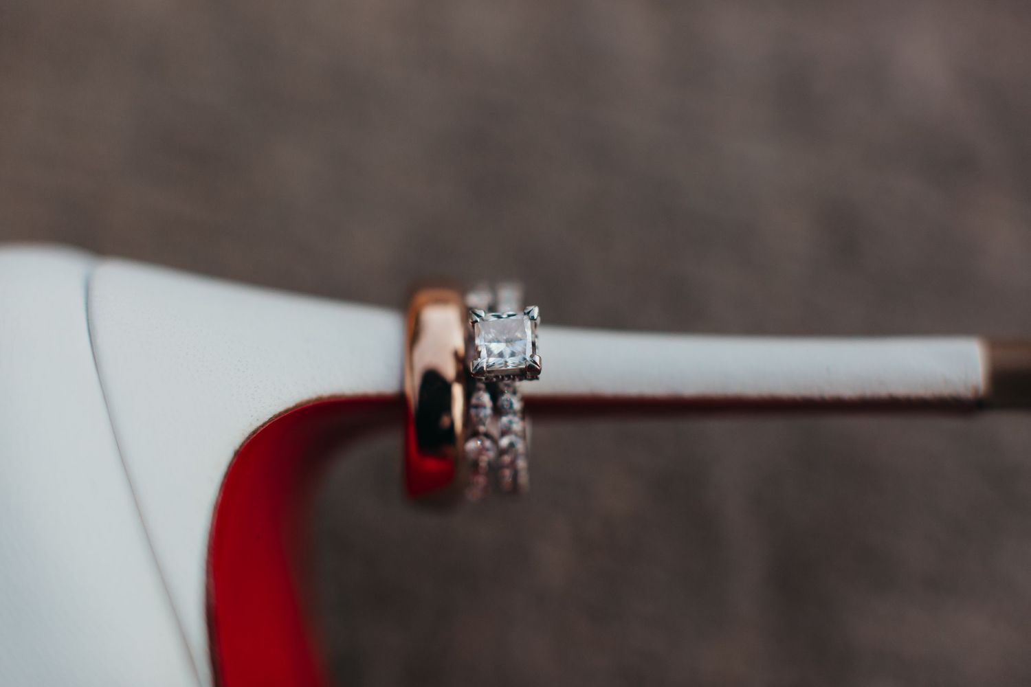 Close-up of diamond wedding rings on white and red surface.