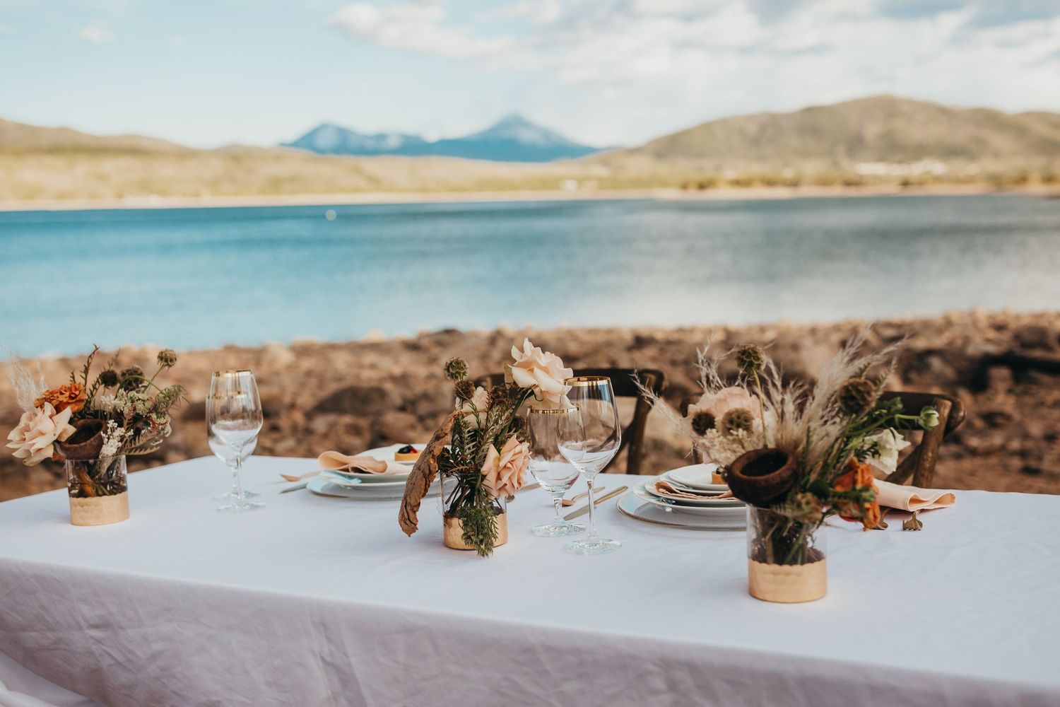 Lakeside table setting with dried floral arrangements and mountain vista background.