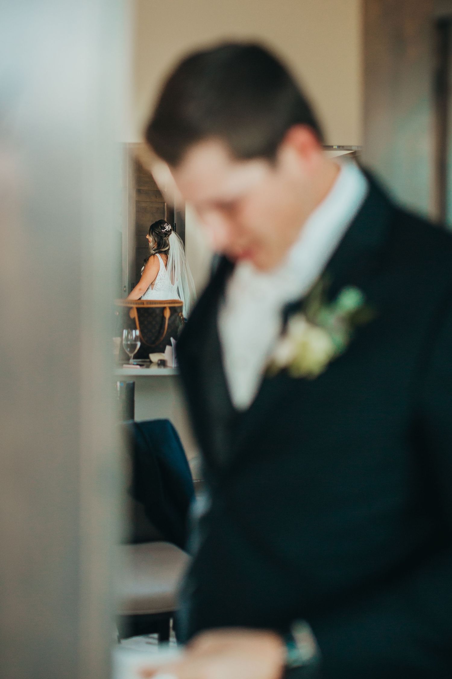 Detail shot of a groom in a black tuxedo and boutonniere preparing before the ceremony.