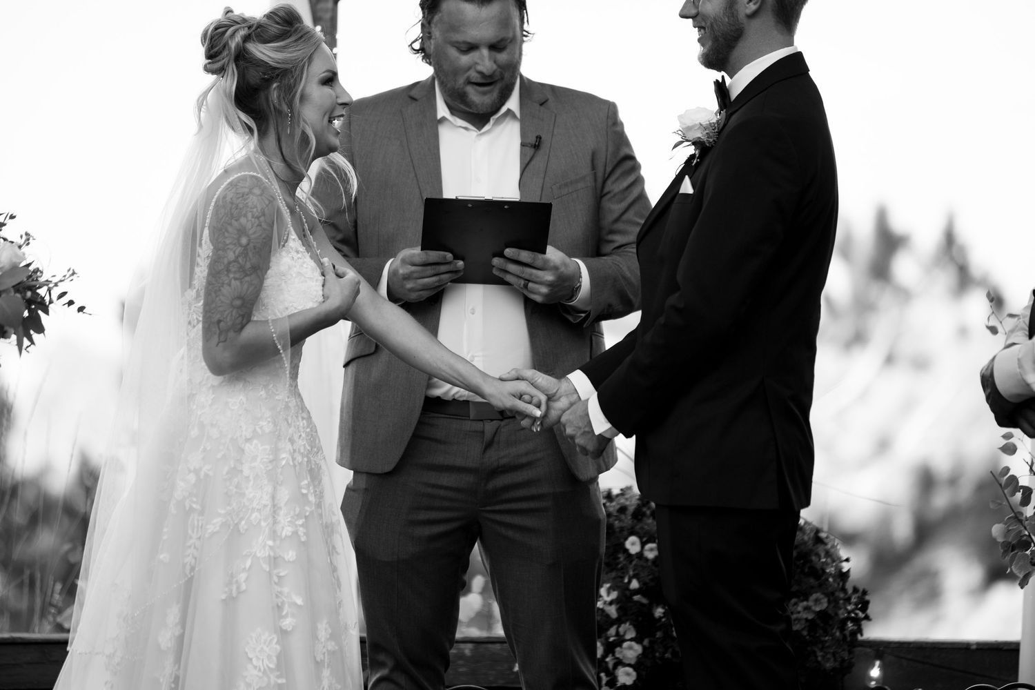 A black and white photograph of a wedding ceremony with three people standing together.