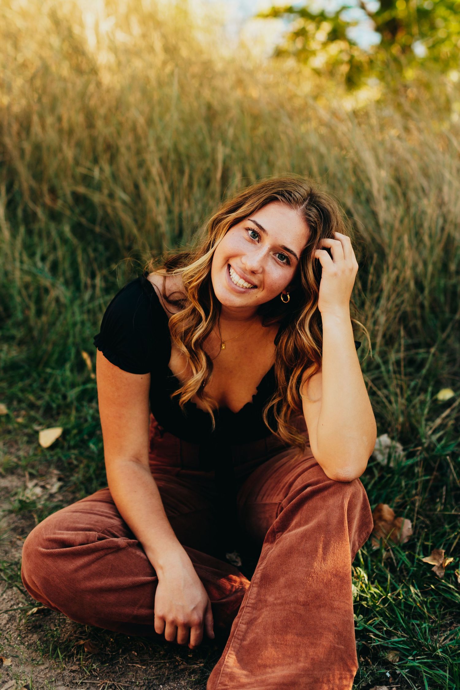 Portrait in golden field with natural sunlight and greenery in background.