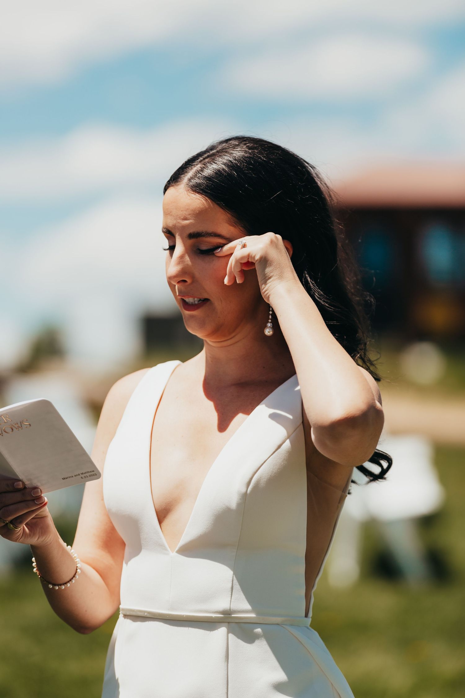 Outdoor bridal portrait showing elegant white dress while reading a note.