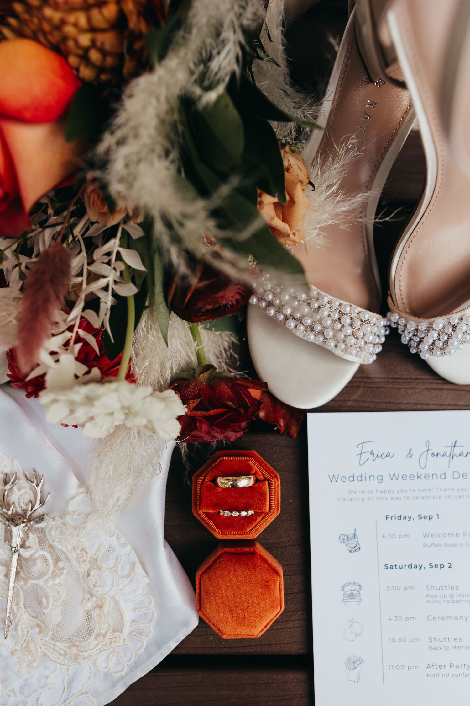 Wedding details flat lay with bridal shoes, rings, invitation and floral decorations.