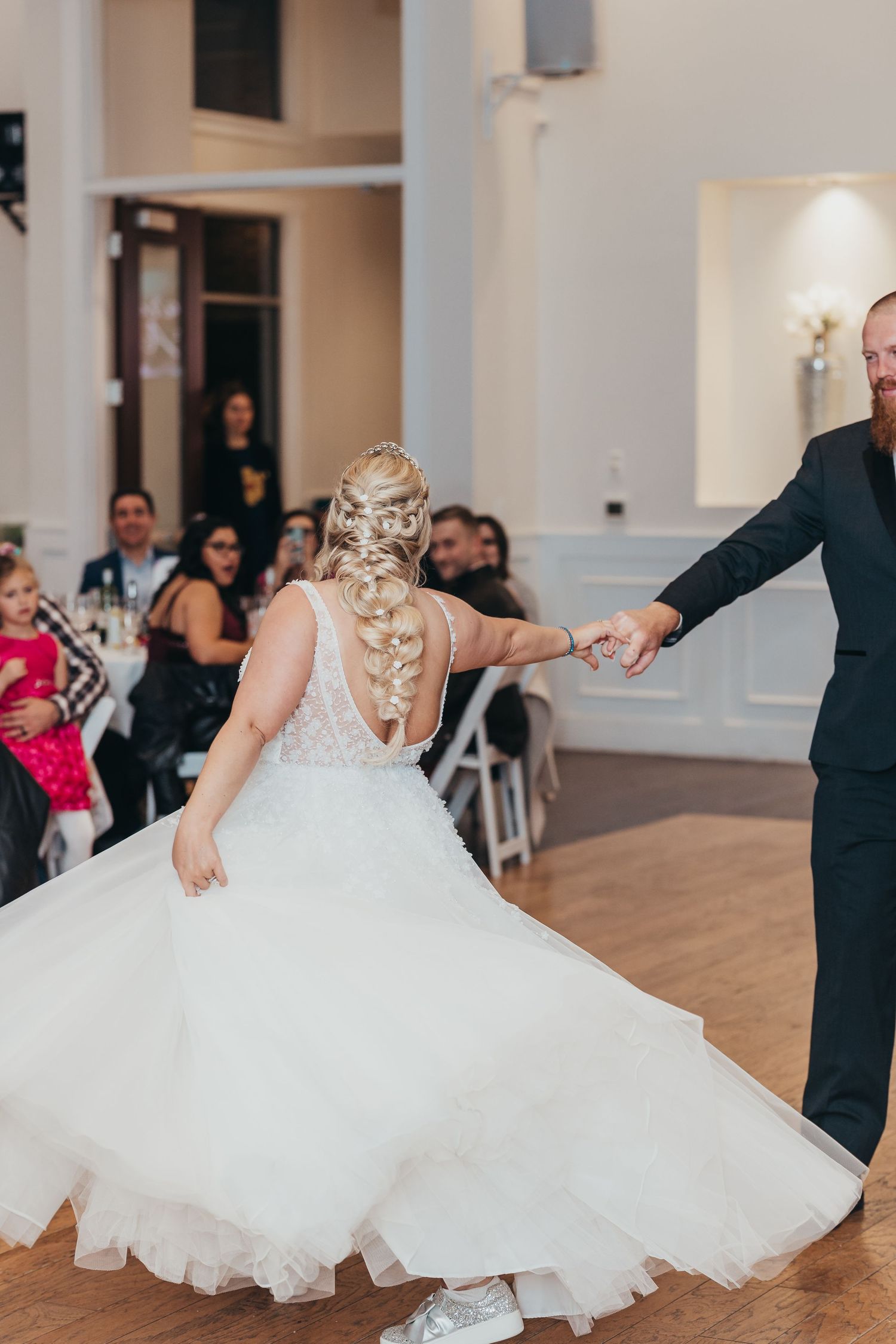 Couple dancing together during their wedding reception in an elegant white-walled venue.