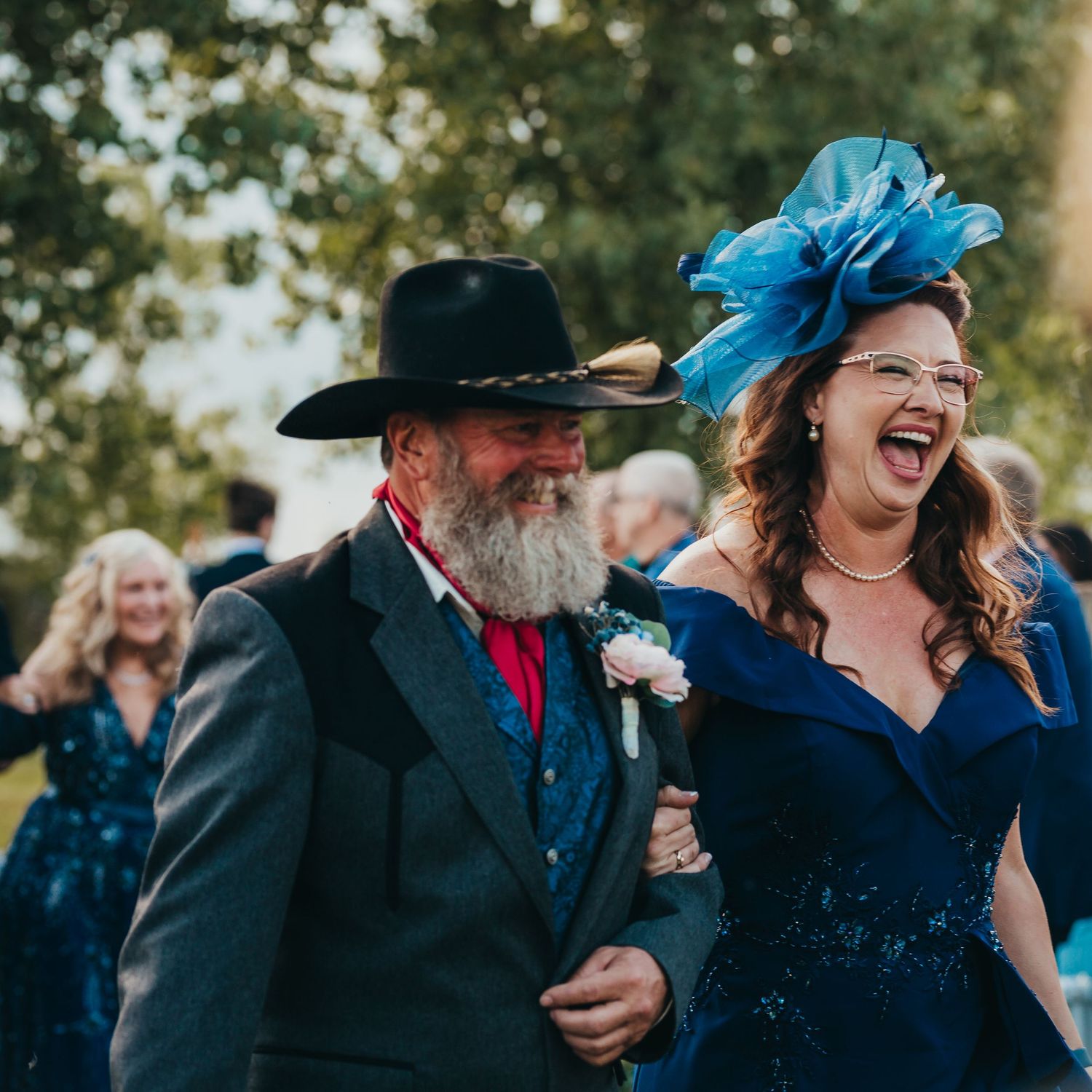 Wedding attendees share a joyful moment in formal attire with vibrant blue accessories.