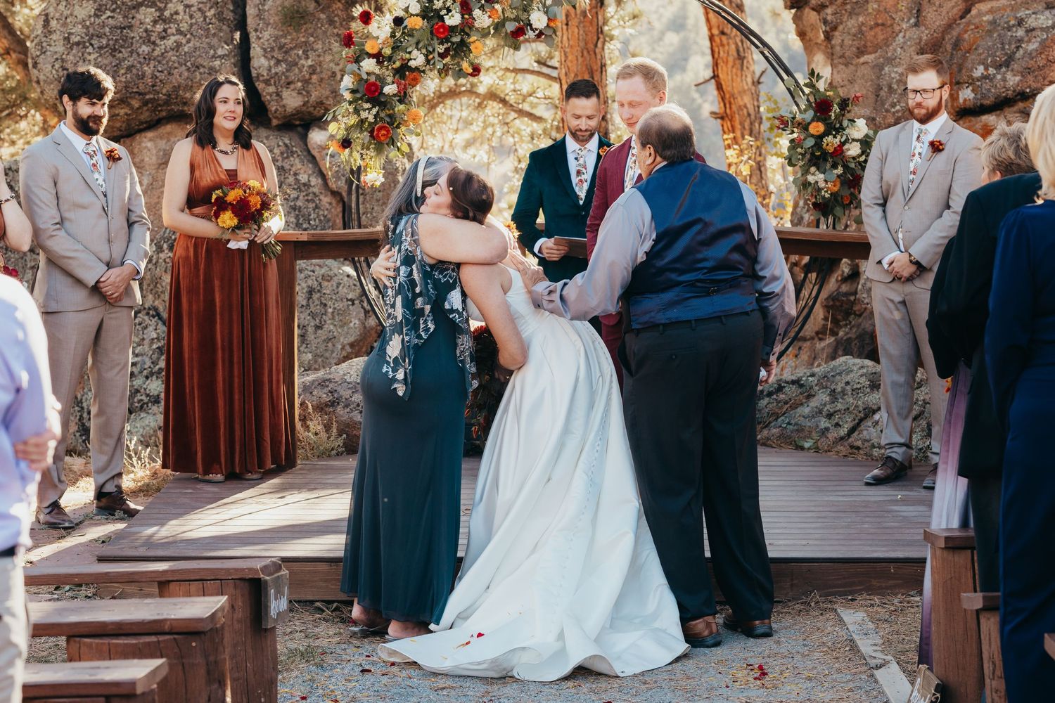 Outdoor wedding ceremony with stone arch backdrop and floral decorations.