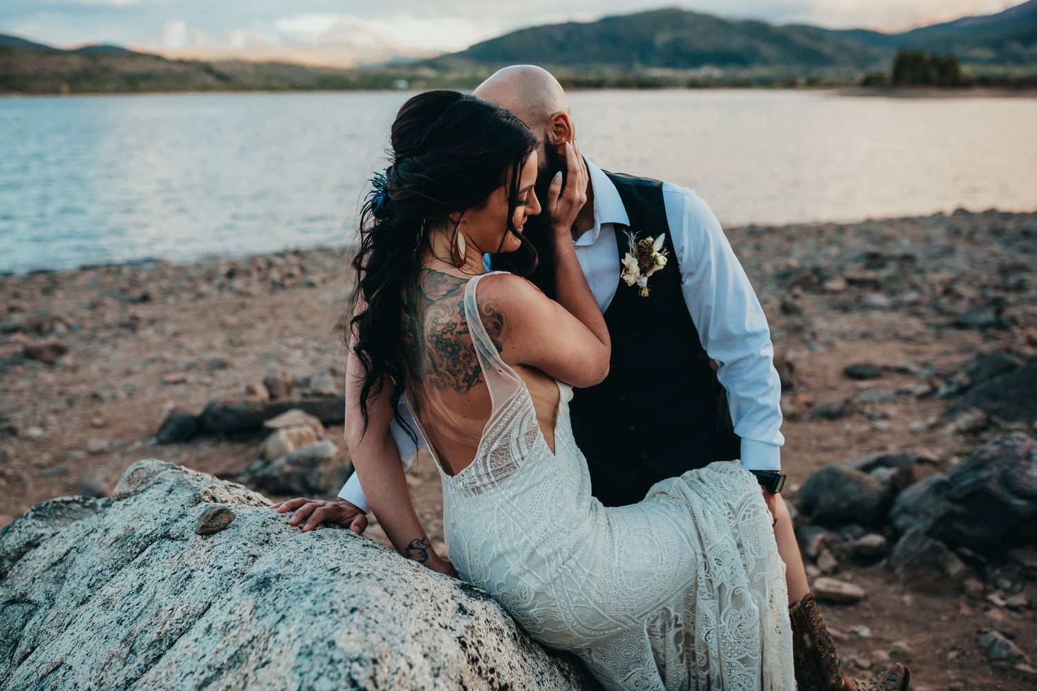 Romantic wedding moment captured against scenic mountain lake.