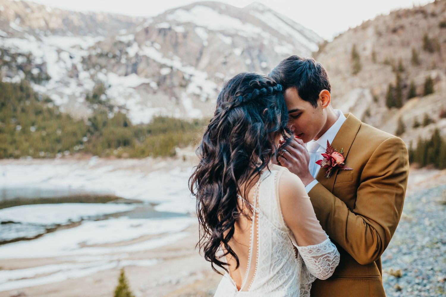 Intimate wedding moment captured against a backdrop of snow-capped mountains and a frozen lake.