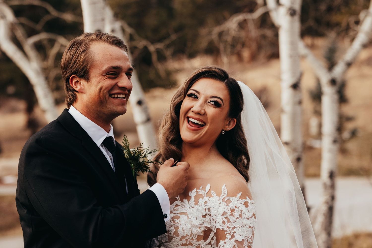 A joyful candid moment shared between newlyweds outdoors with natural lighting.