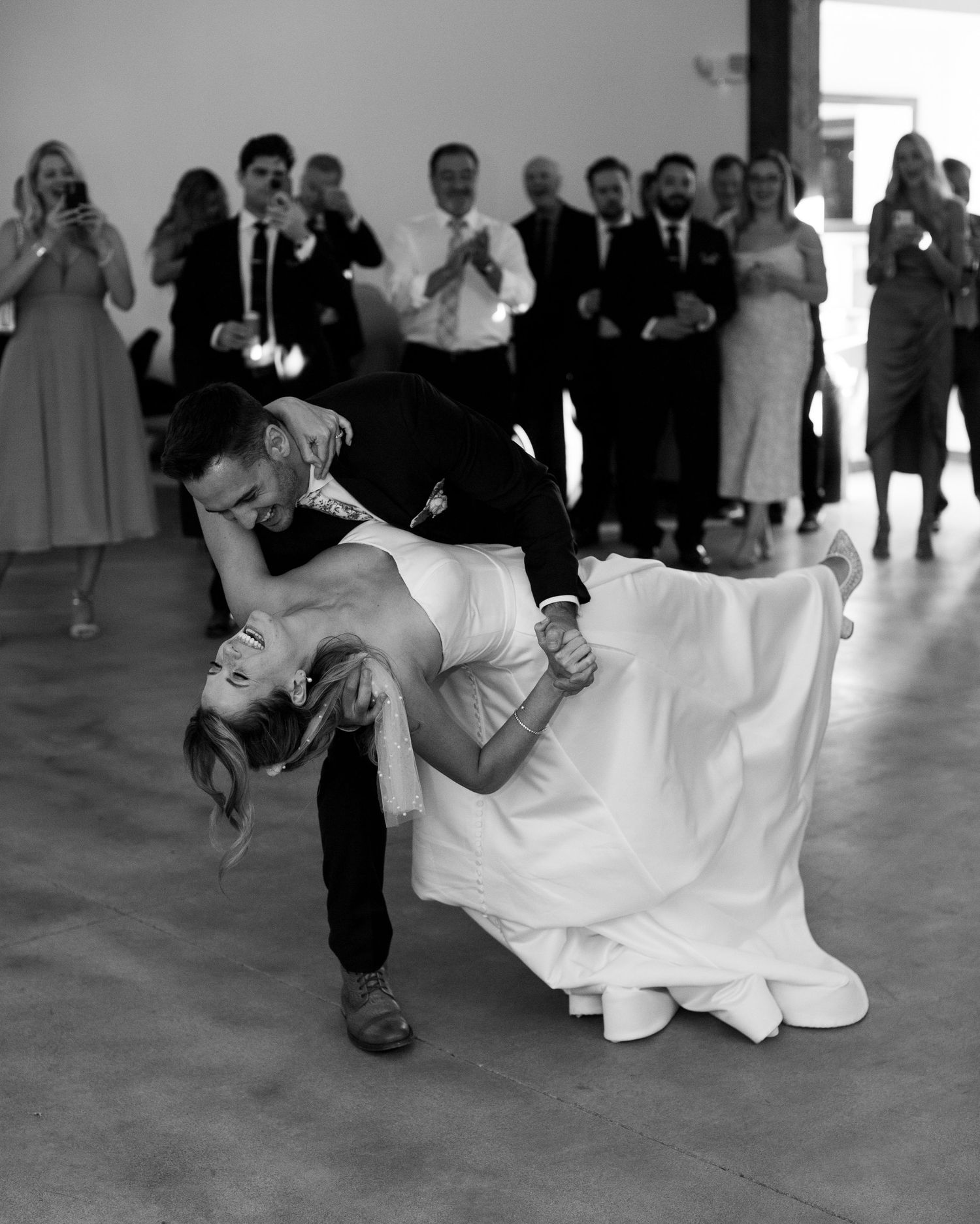 Dramatic black and white first dance dip at indoor wedding reception.