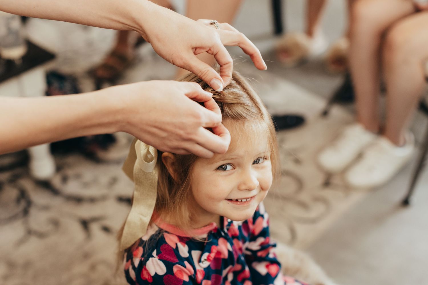 Hands styling a young child's hair during wedding preparations.