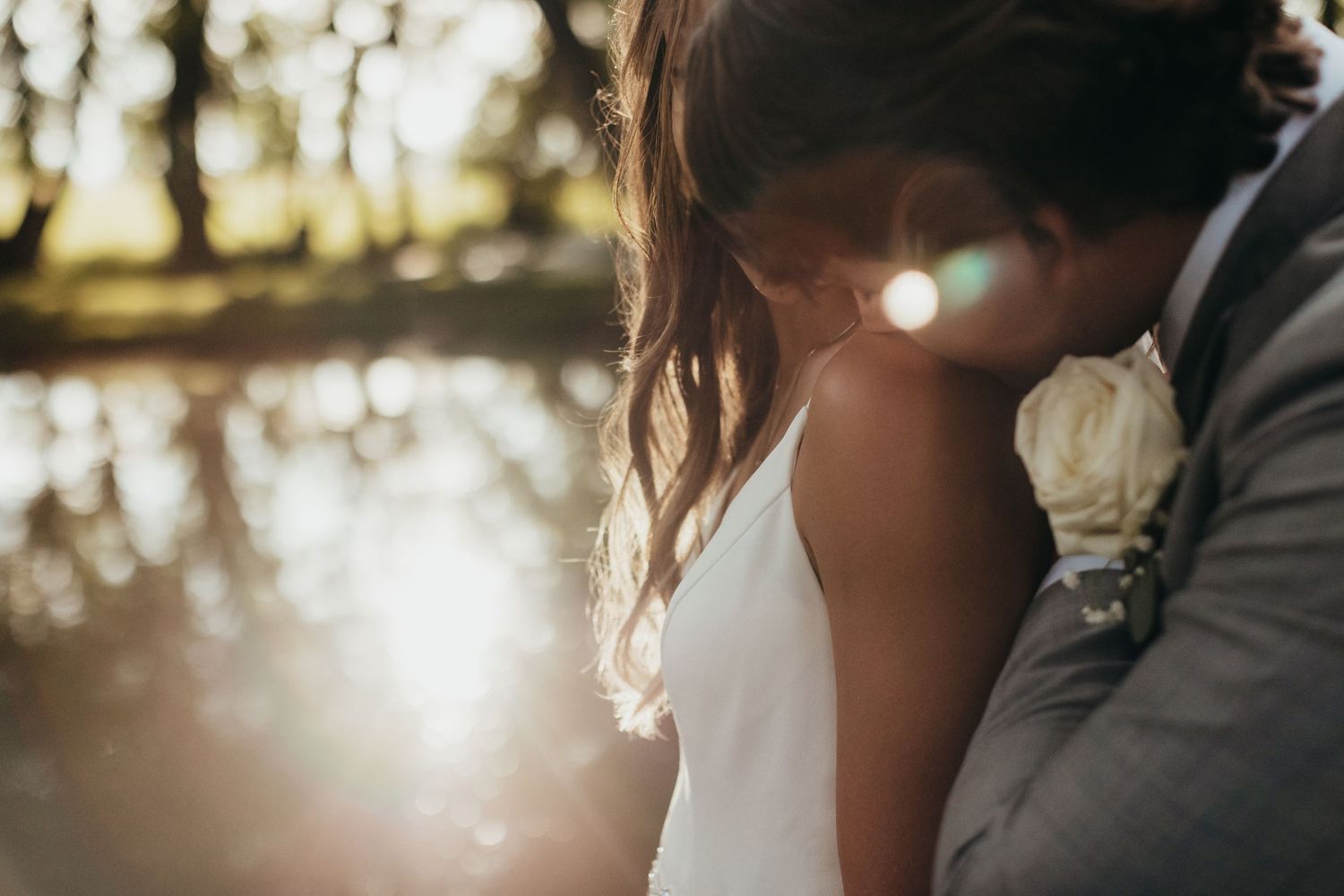 Artistic silhouette of couple with sun flare during sunset wedding portraits.