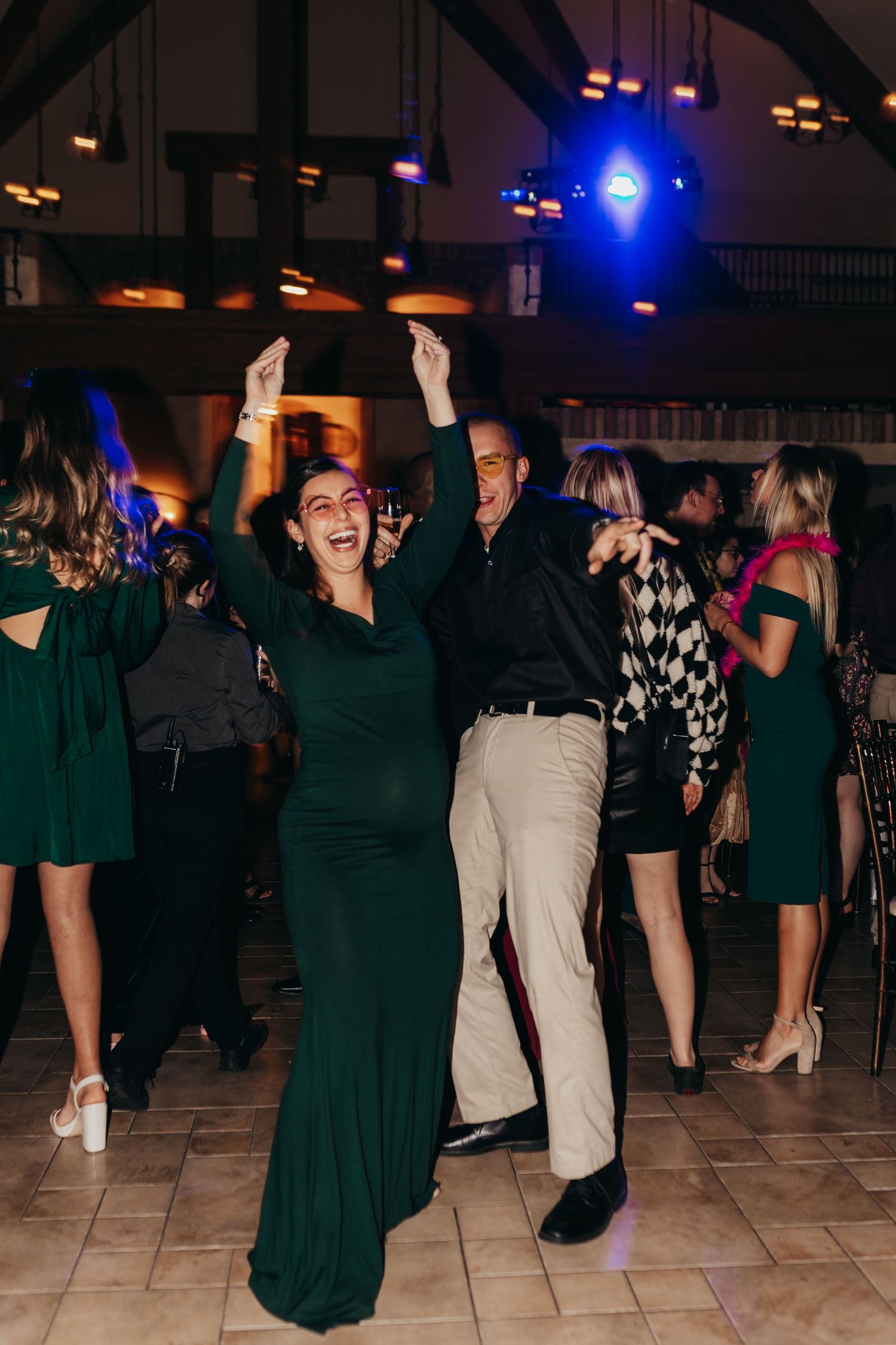 Guests dancing under blue stage lights at a formal event with a woman in green dress.