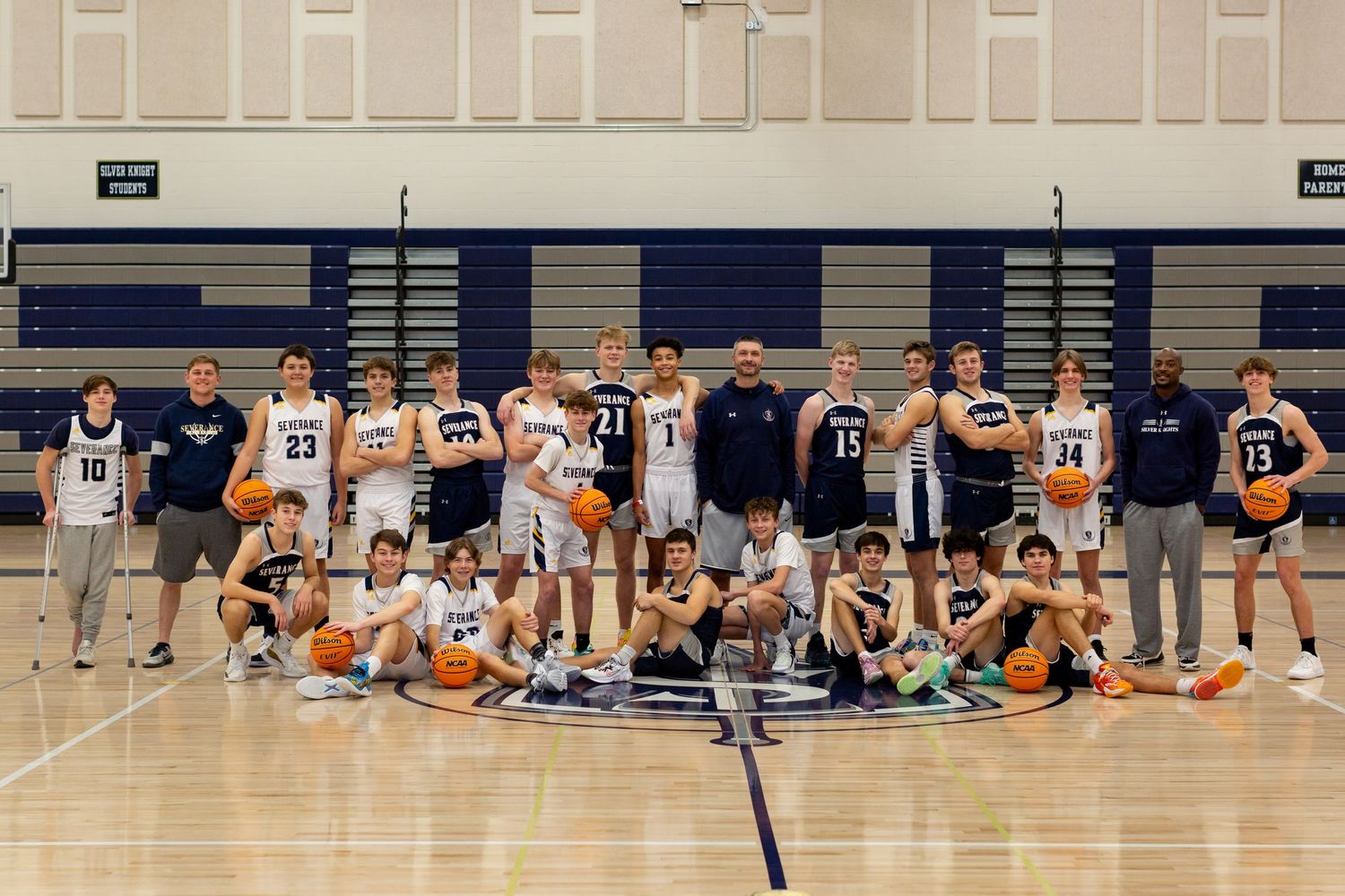 Basketball team poses together on indoor court after practice or game.