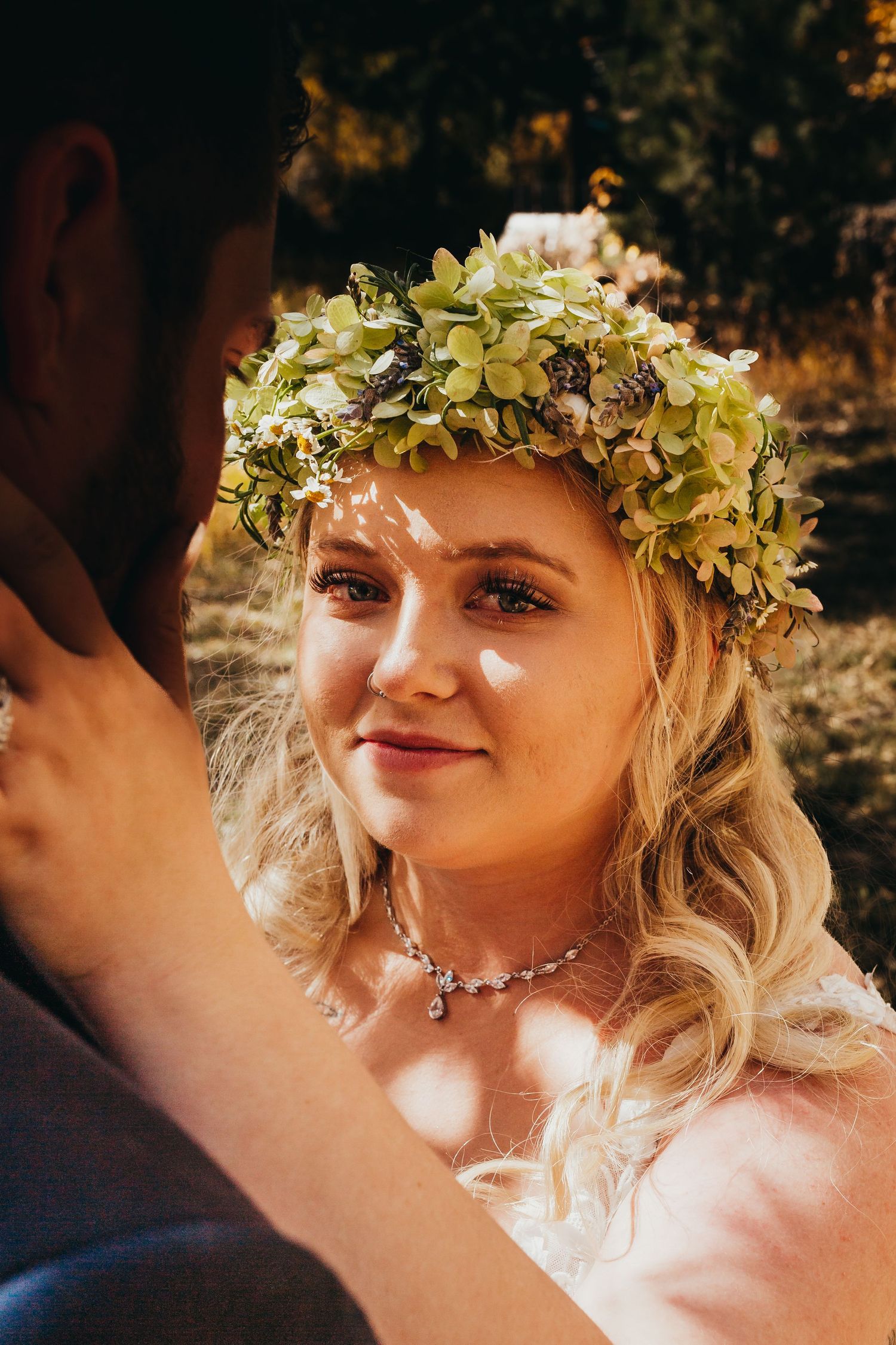 Bride wearing floral crown and lace dress in autumn sunlight.