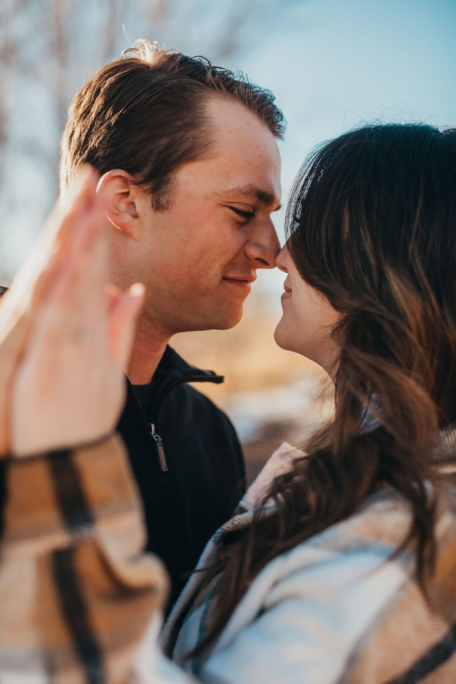 Intimate close-up of couple sharing tender moment outdoors at sunset.