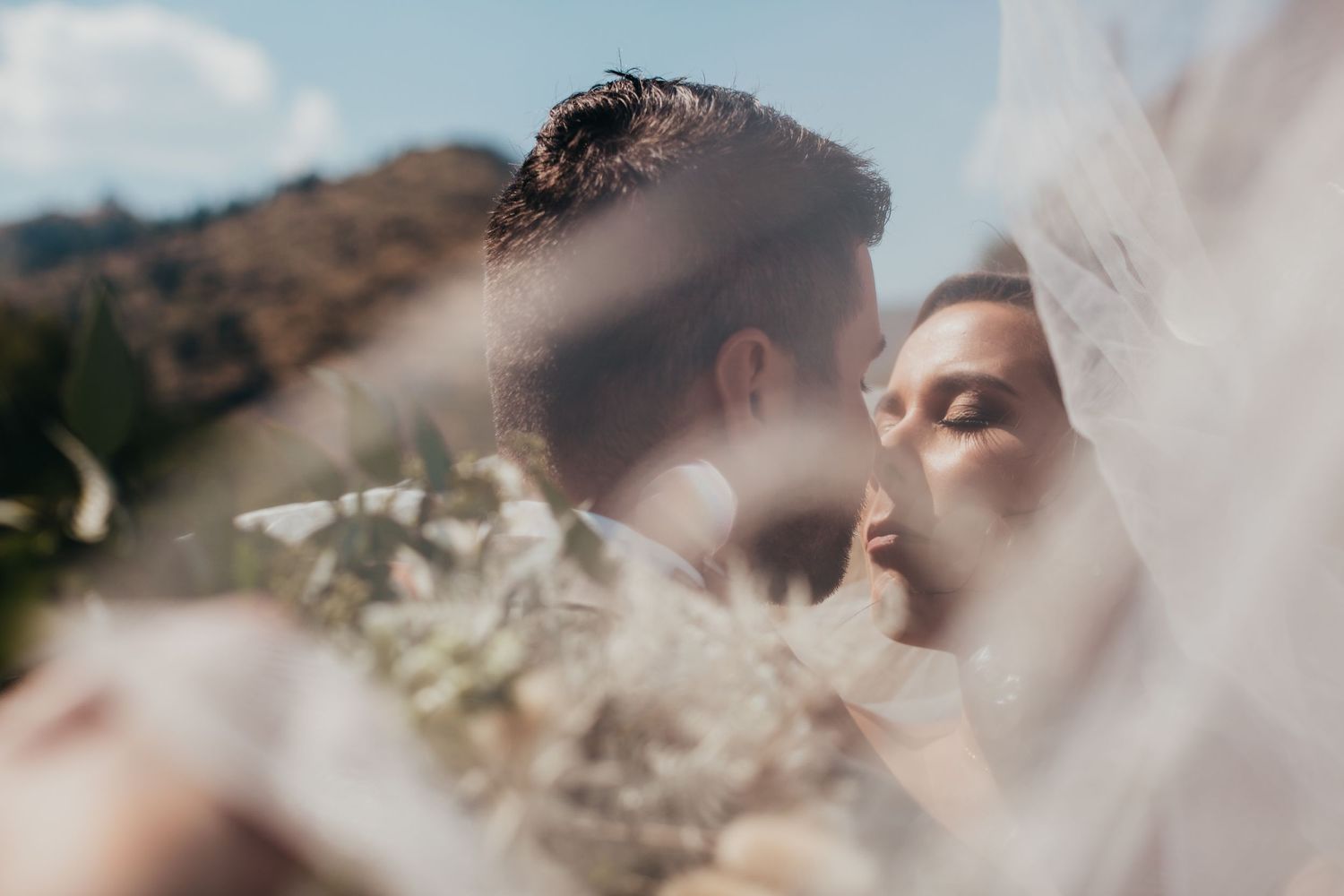 Romantic soft focus wedding photo through veil in mountain landscape.