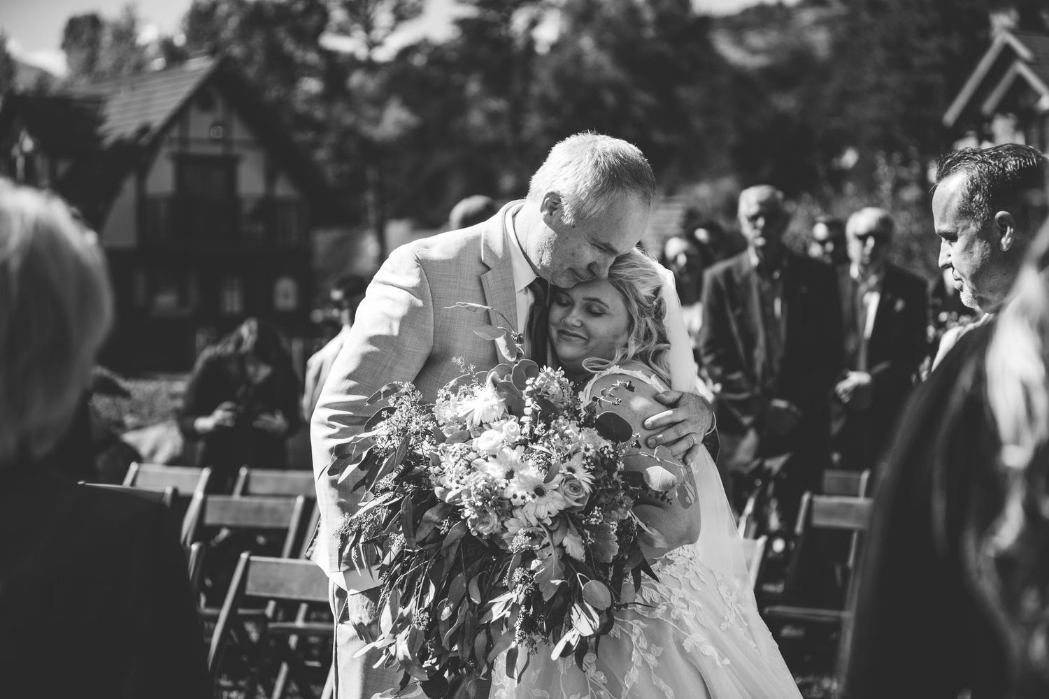 An intimate wedding ceremony moment captured in black and white with guests watching.