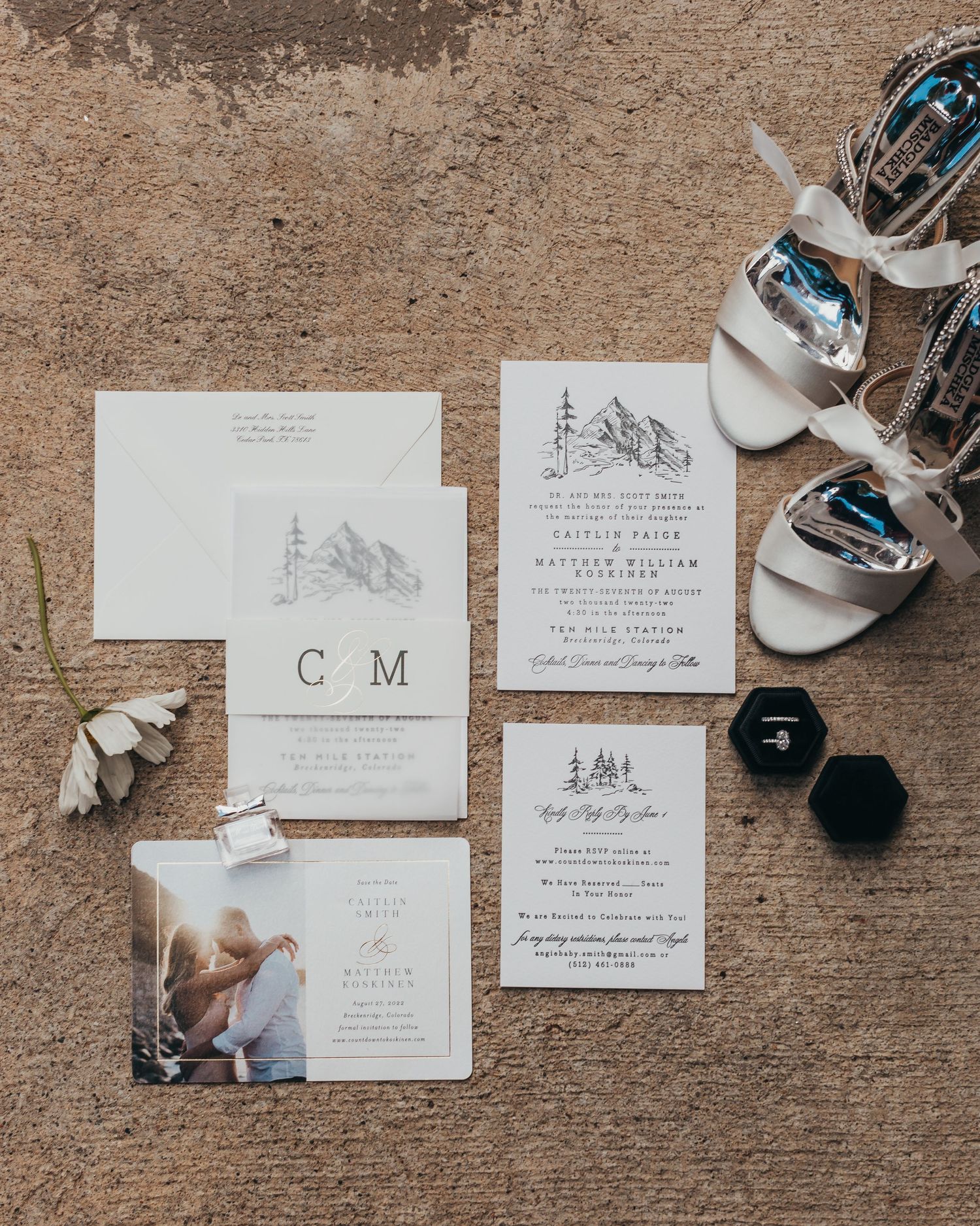 Elegant wedding invitation suite with mountain motif alongside bridal accessories.
