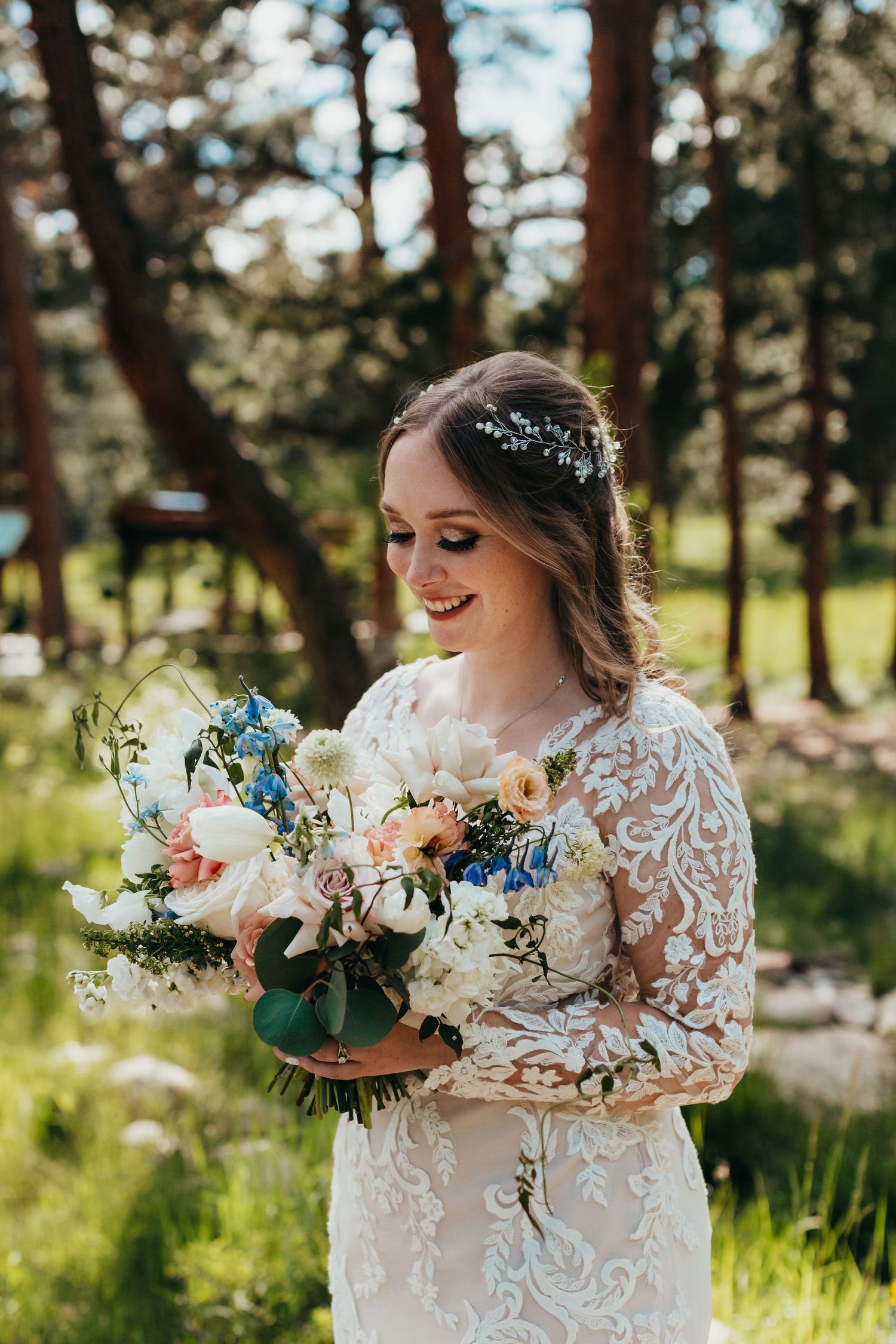 Bride holding beautiful bouquet with blue and white flowers in outdoor setting.