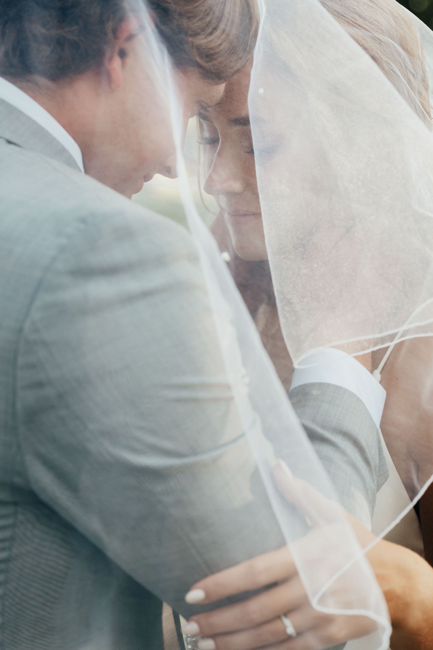 Intimate close-up through bridal veil during outdoor wedding ceremony.