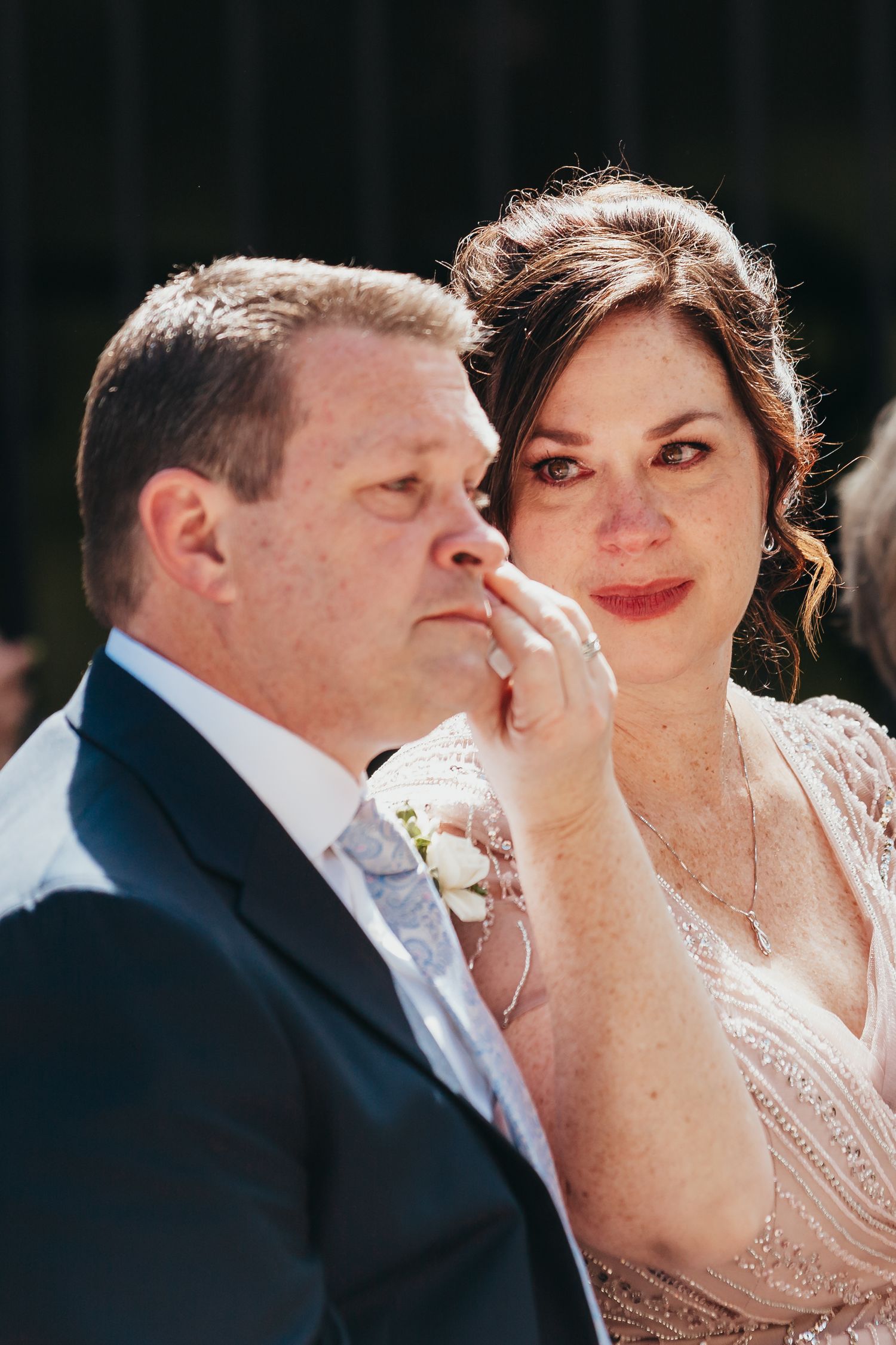 A tender moment captured during an outdoor wedding ceremony on a sunny day.