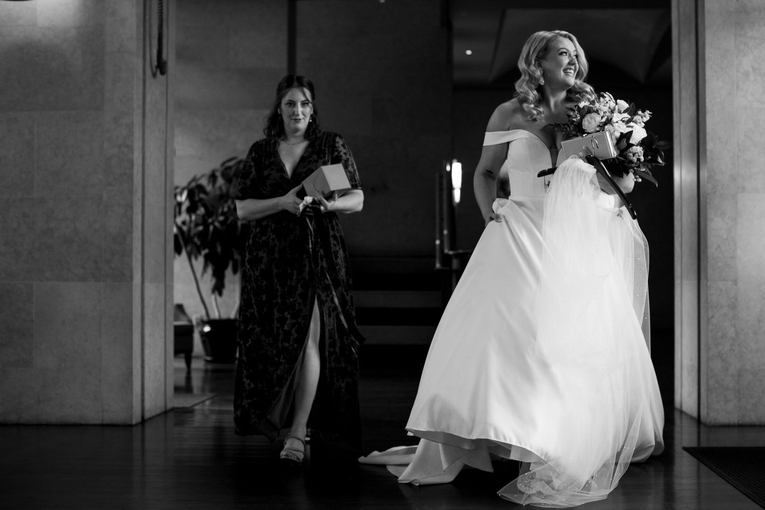 A black and white photograph capturing movement in a wedding venue hallway.