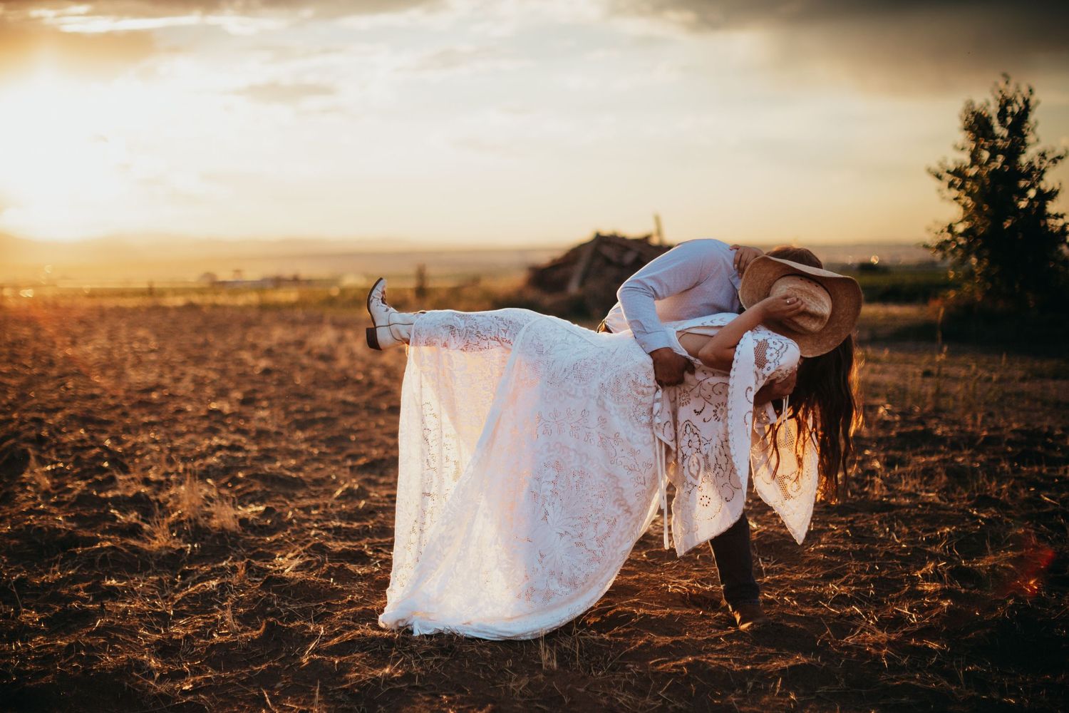Ethereal bridal portrait with flowing white dress against golden sunset landscape.