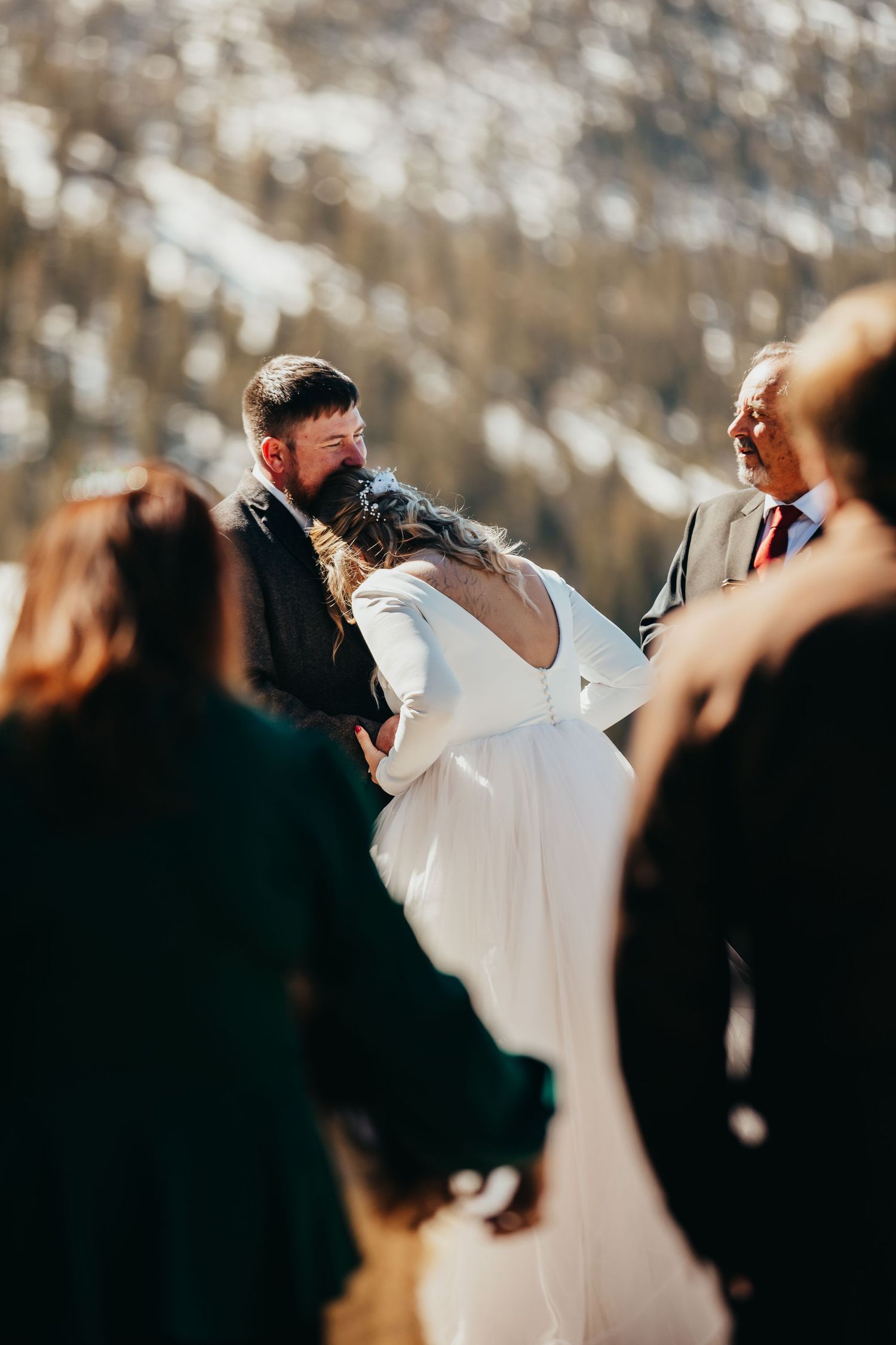 An outdoor winter wedding ceremony with guests gathering around the couple.