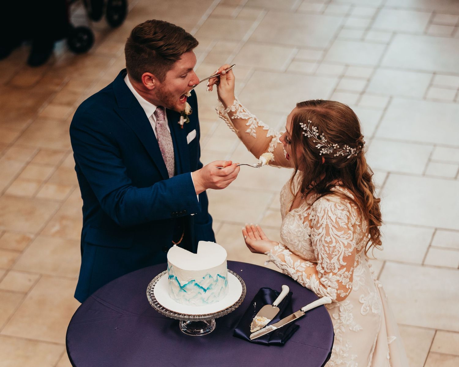 A couple sharing a playful cake-feeding moment at their wedding reception.
