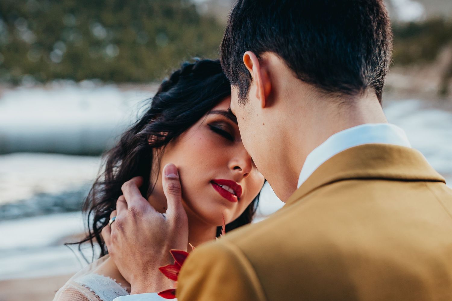 Romantic close-up moment between newlyweds with mountain scenery in background.