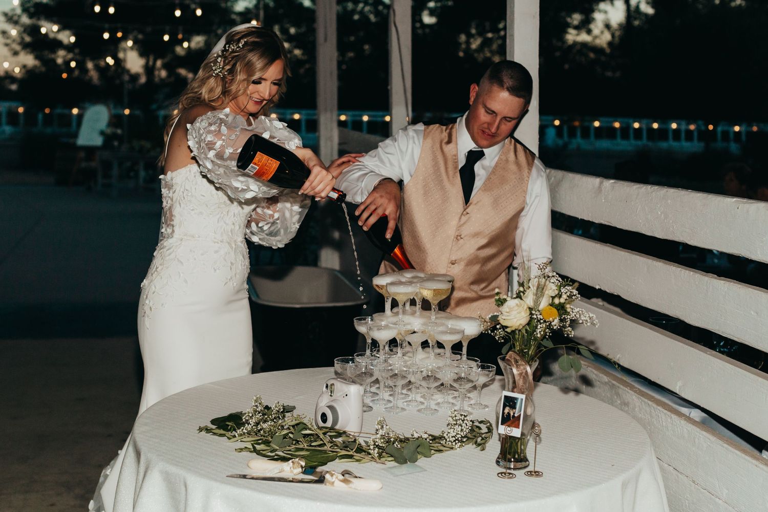 Wedding couple pouring champagne at their reception table.