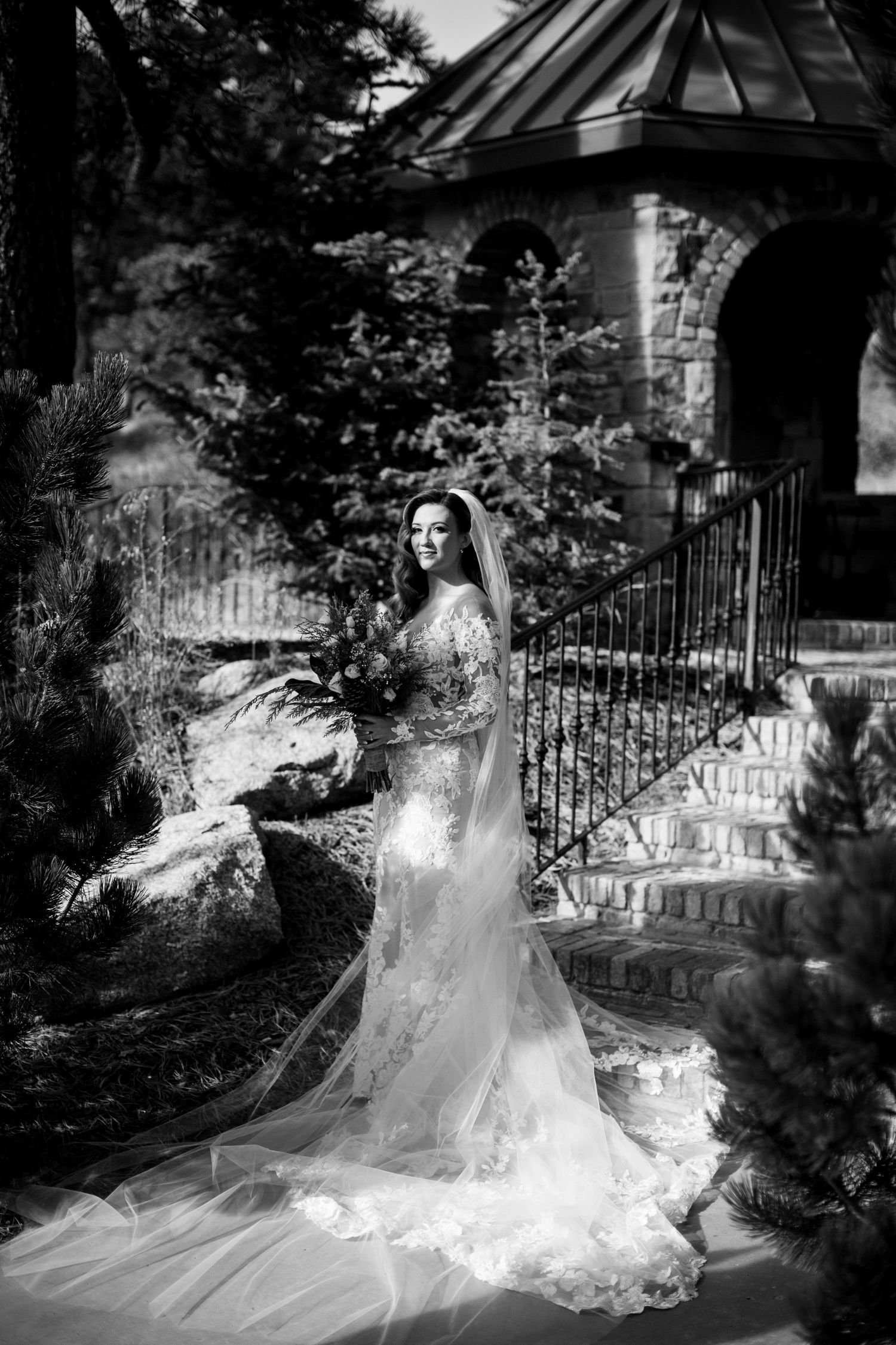 Black and white bridal portrait near stone gazebo with flowing veil.
