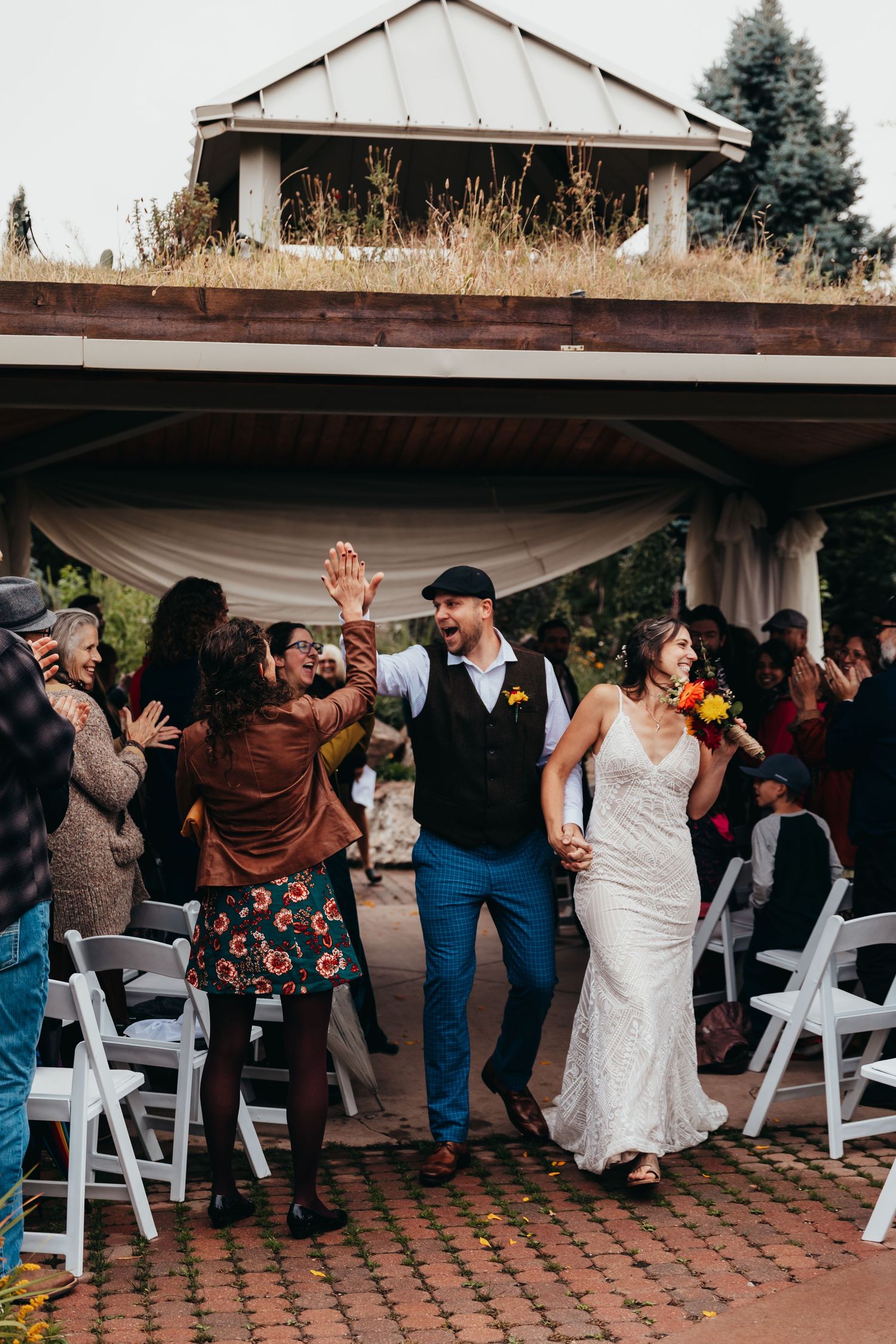Newlyweds celebrate with guests during lively outdoor reception under covered venue.