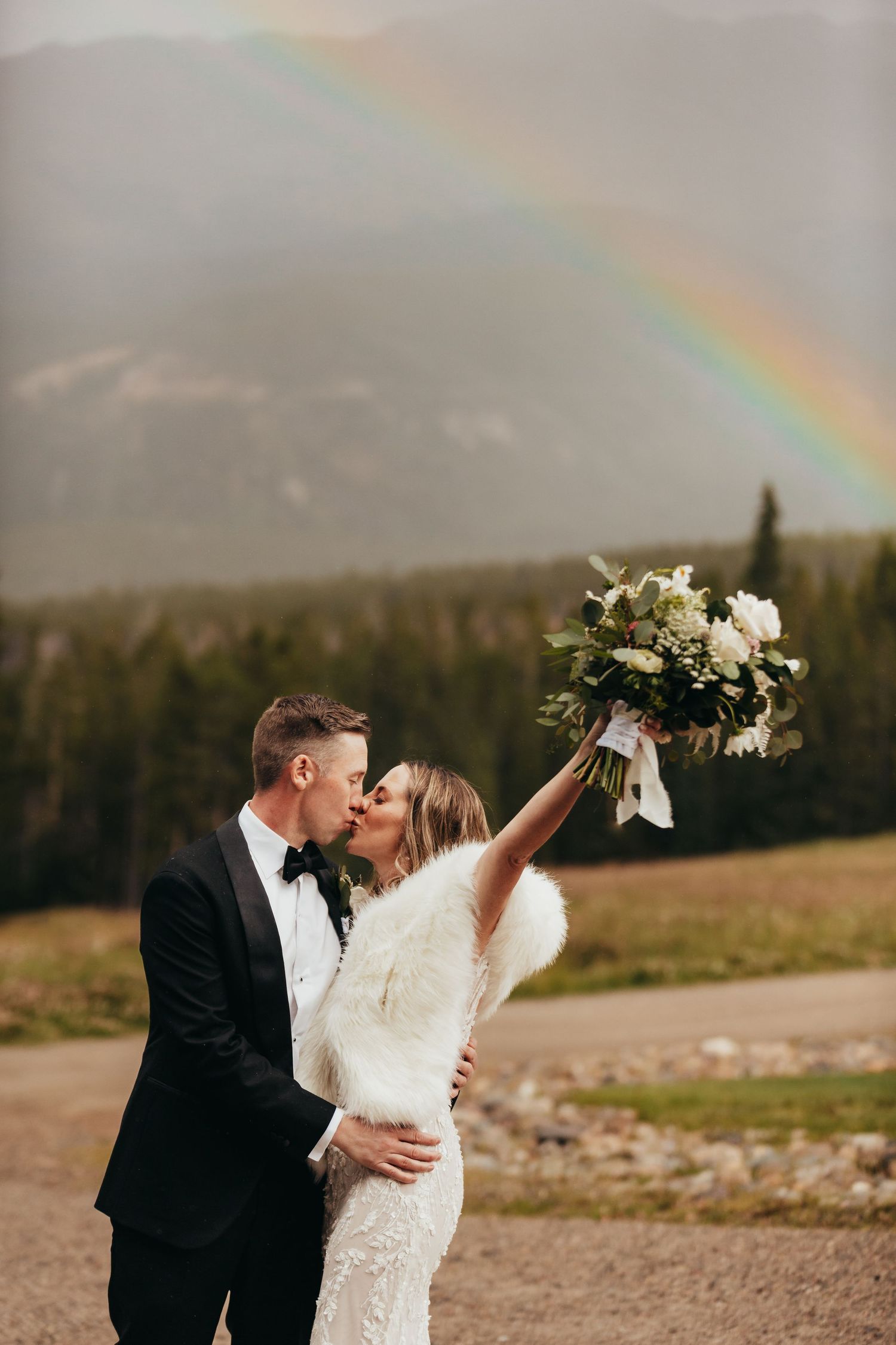 Beautiful rainbow appears over mountain landscape during wedding photoshoot.