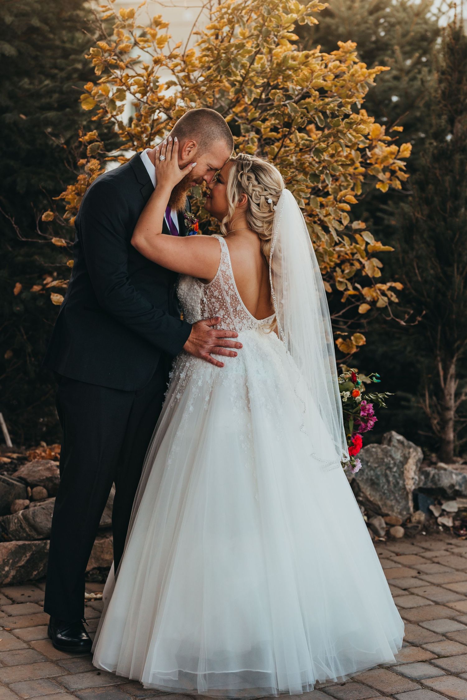 Intimate wedding moment captured against golden autumn foliage.