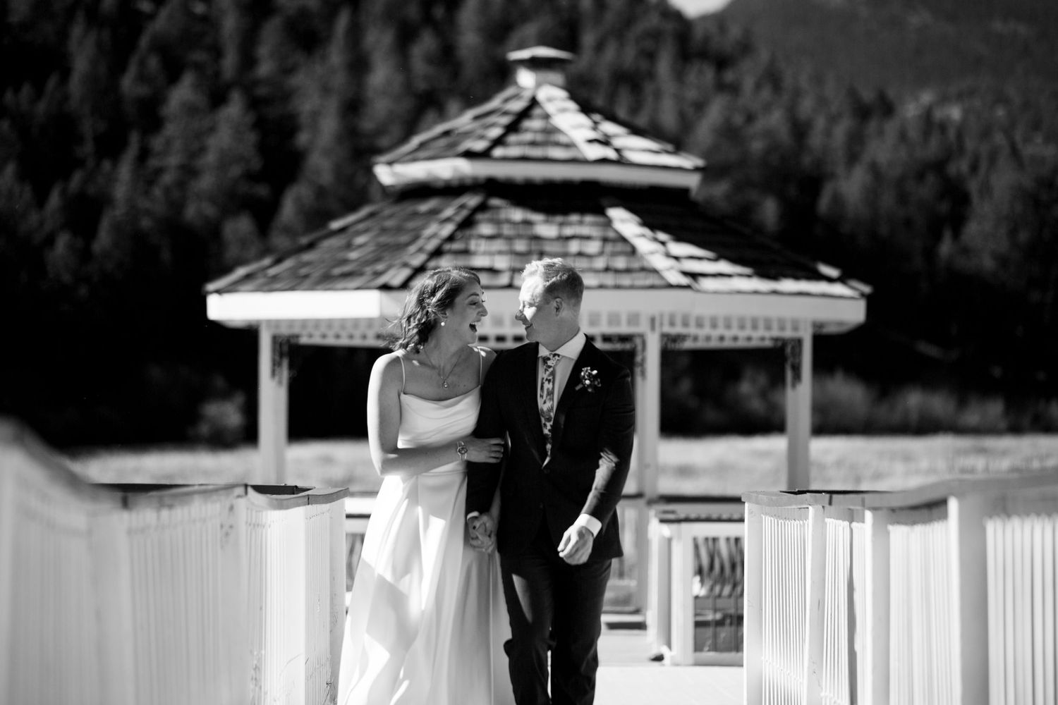 Black and white photo of a couple walking along a gazebo walkway.
