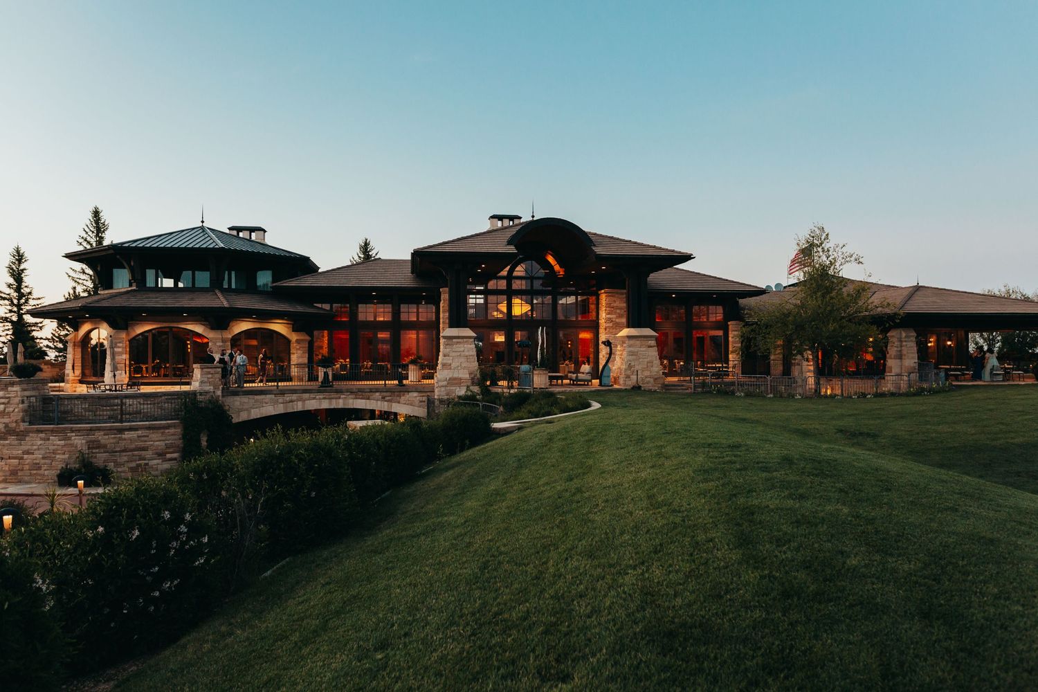 Modern luxury mansion with manicured lawn at sunset against blue sky.