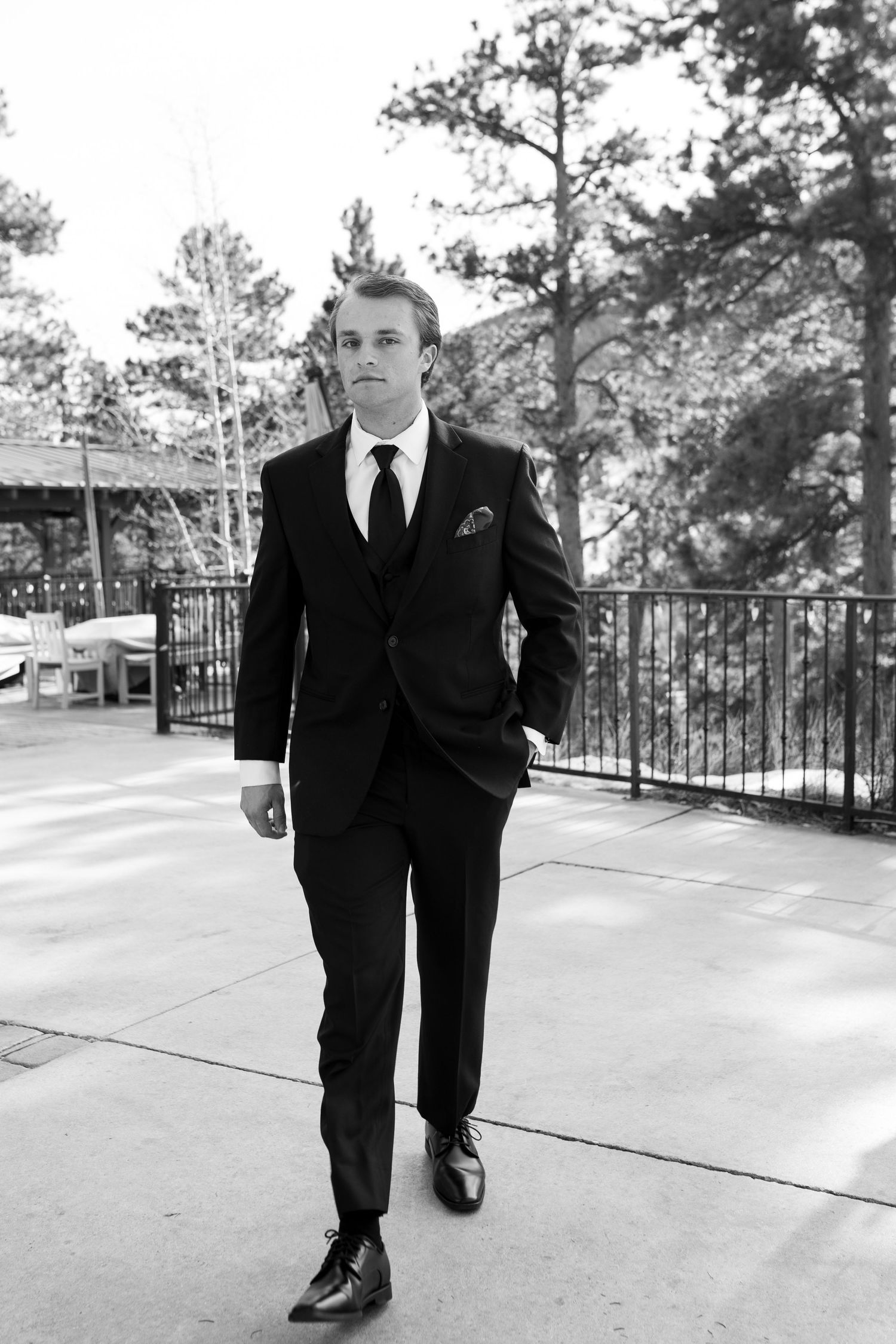 Classic black and white photo of groom walking on outdoor terrace.