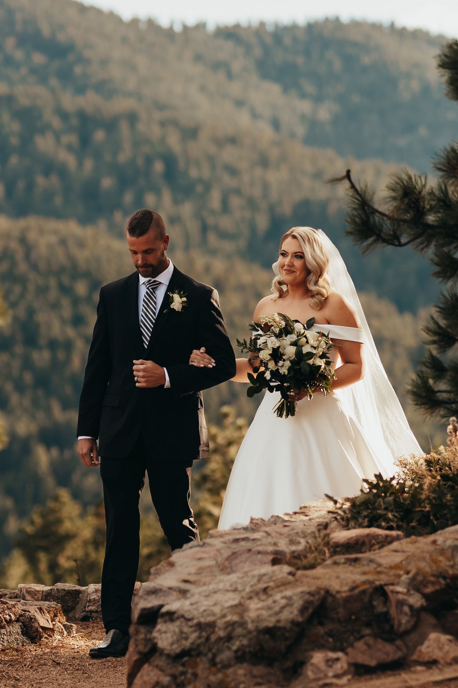 A couple walking along a rocky mountain path during their wedding ceremony.