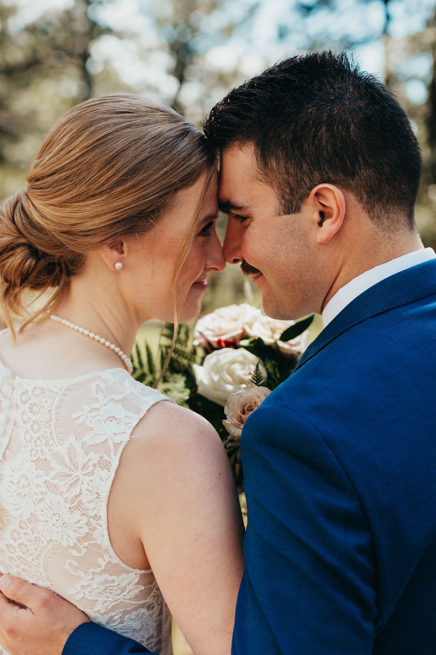 Intimate close-up of newlyweds sharing a tender moment with foreheads touching.