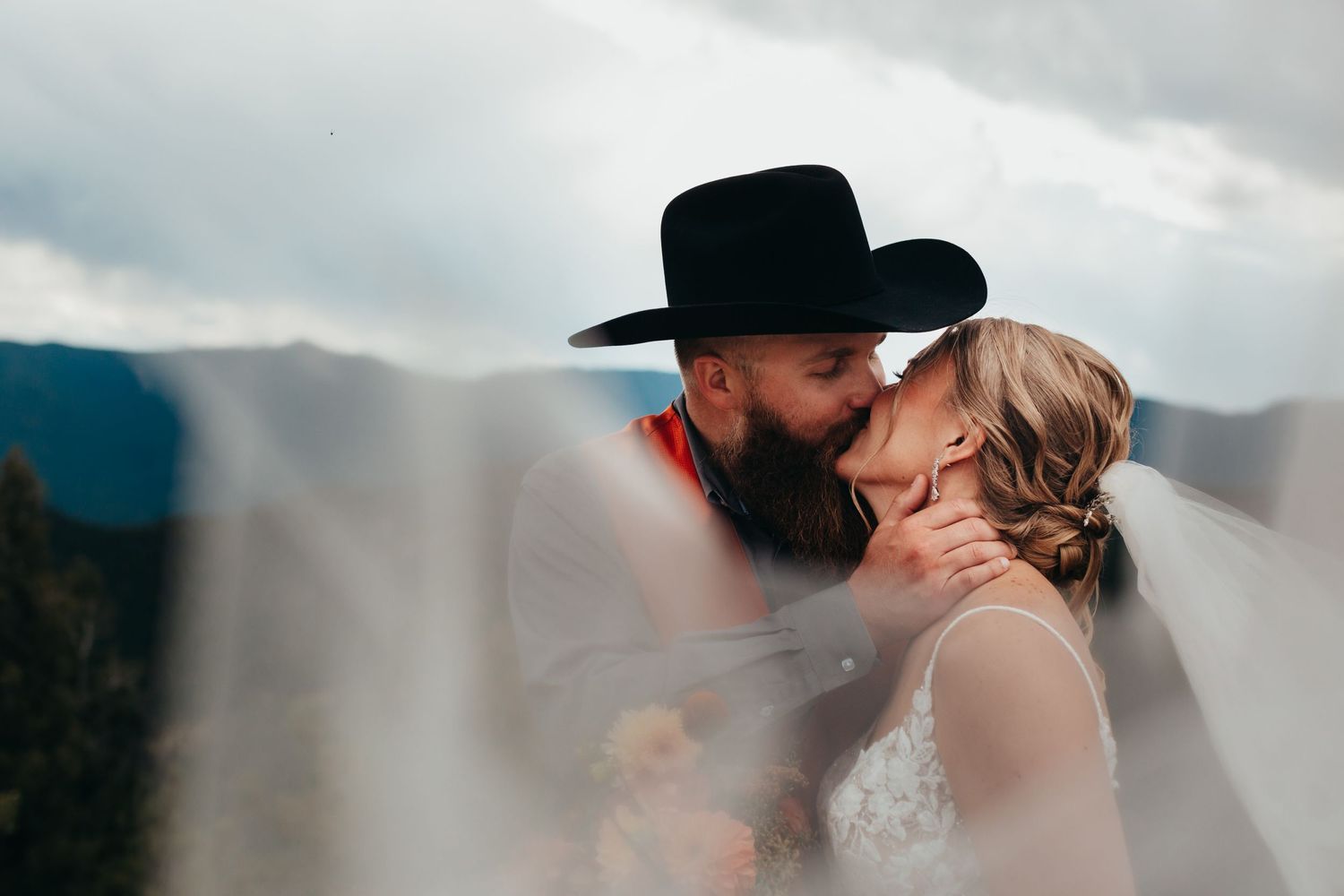 An intimate wedding moment captured against a dramatic mountain landscape.