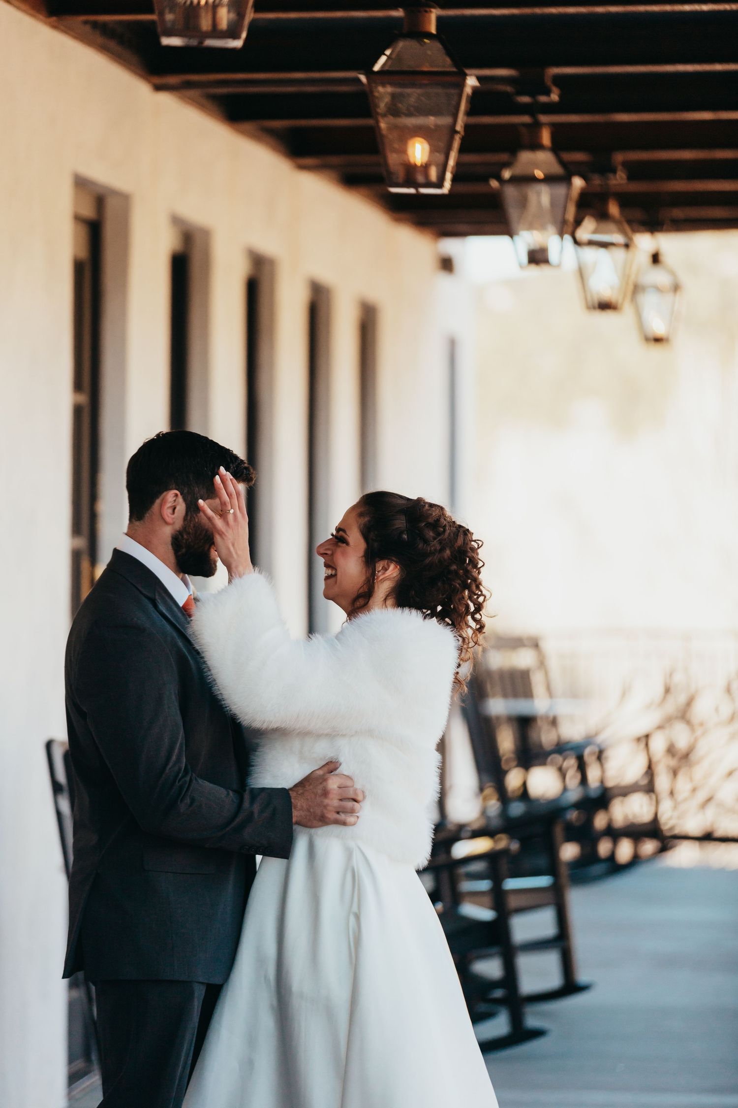 Couple shares intimate moment on porch with hanging lanterns.