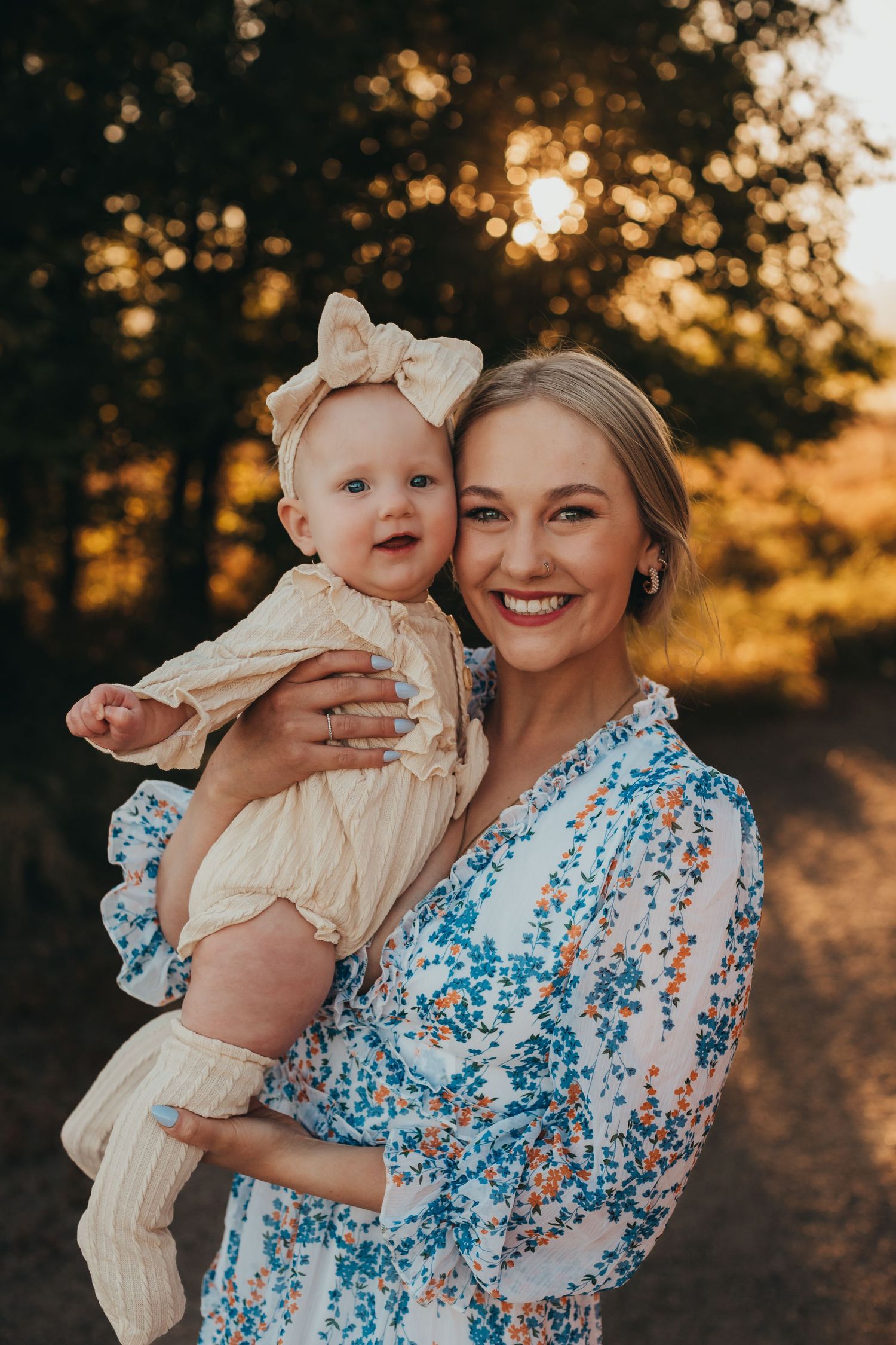 Mother and baby in matching cream and blue outfits pose during sunset outdoor photoshoot.