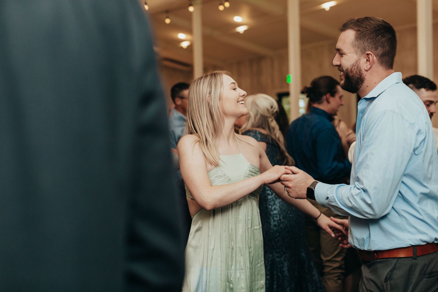 Couples dance together at an indoor wedding reception with soft lighting.