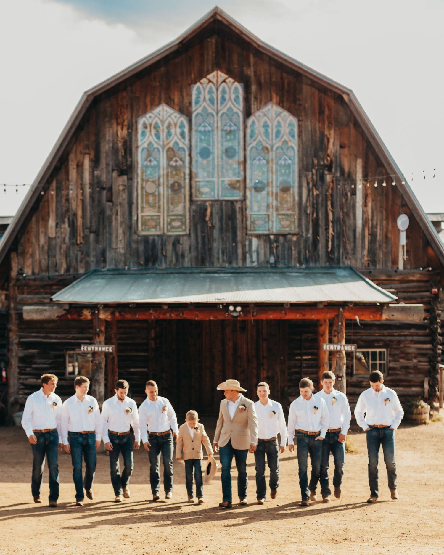 Group photo in front of rustic barn with decorative stained glass windows.