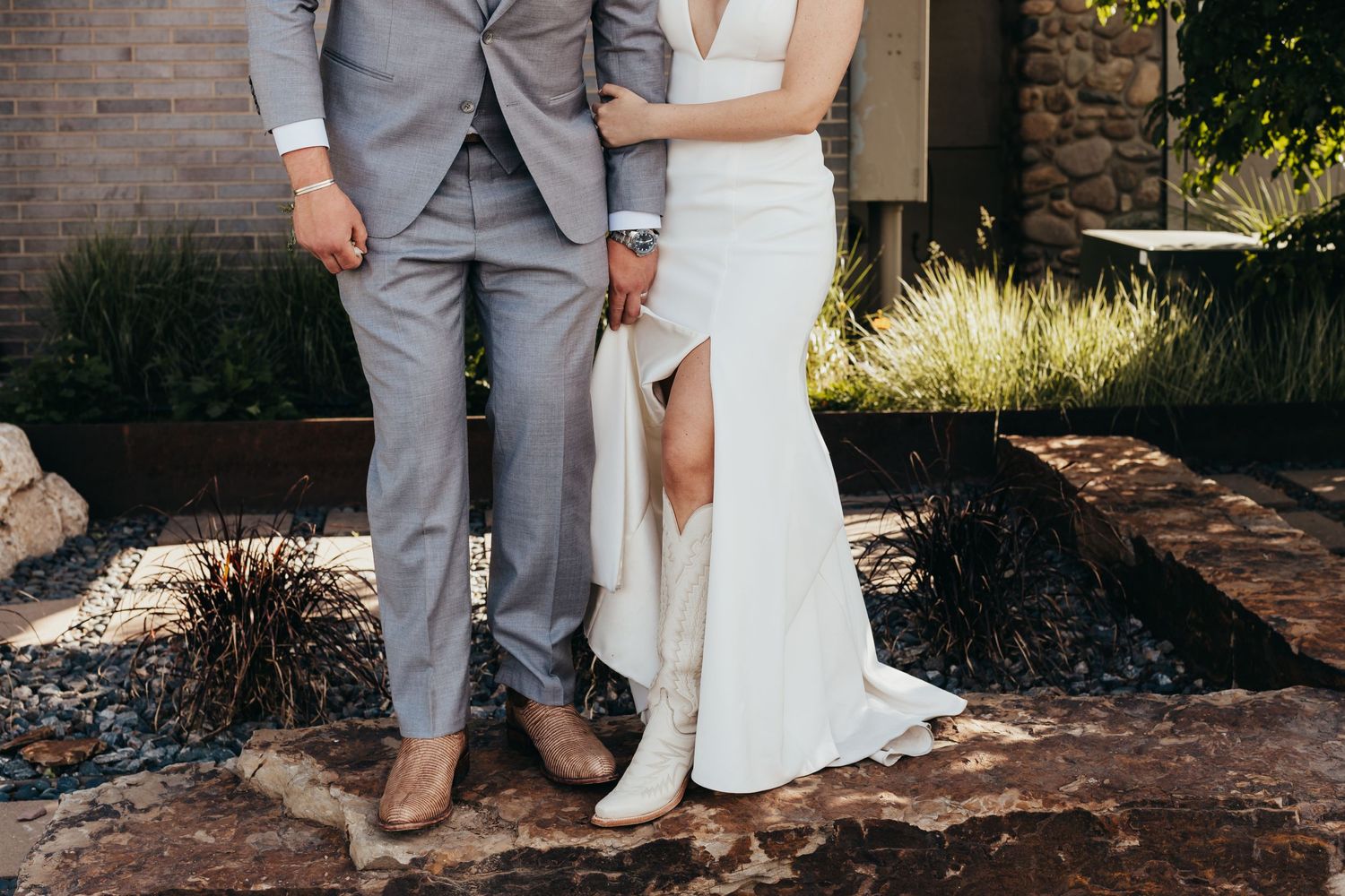 Close up of bride and groom's formal attire showing white dress and gray suit details.