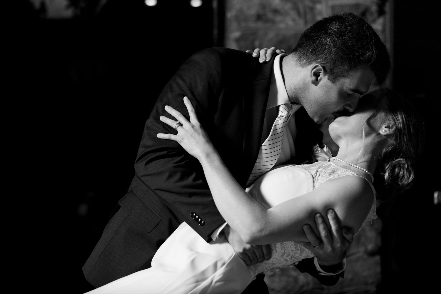 Dramatic black and white dip kiss during wedding first dance.